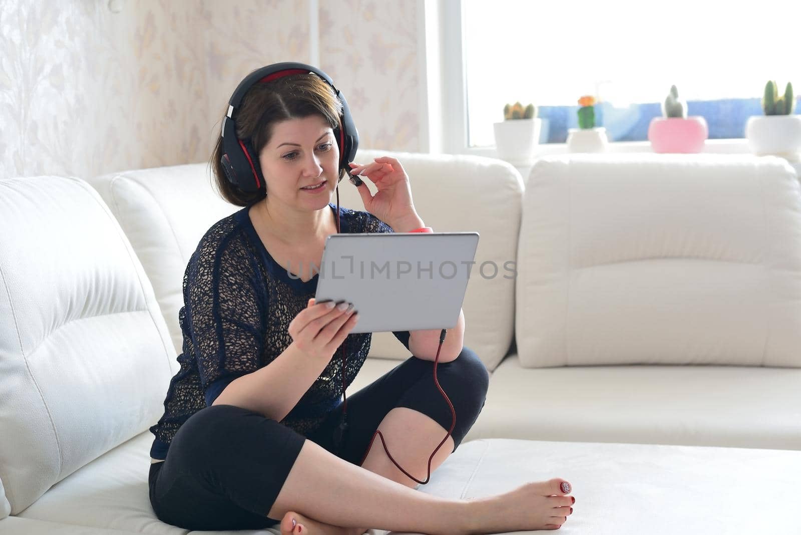 woman working on tablet and wearing headphones by olgavolodina