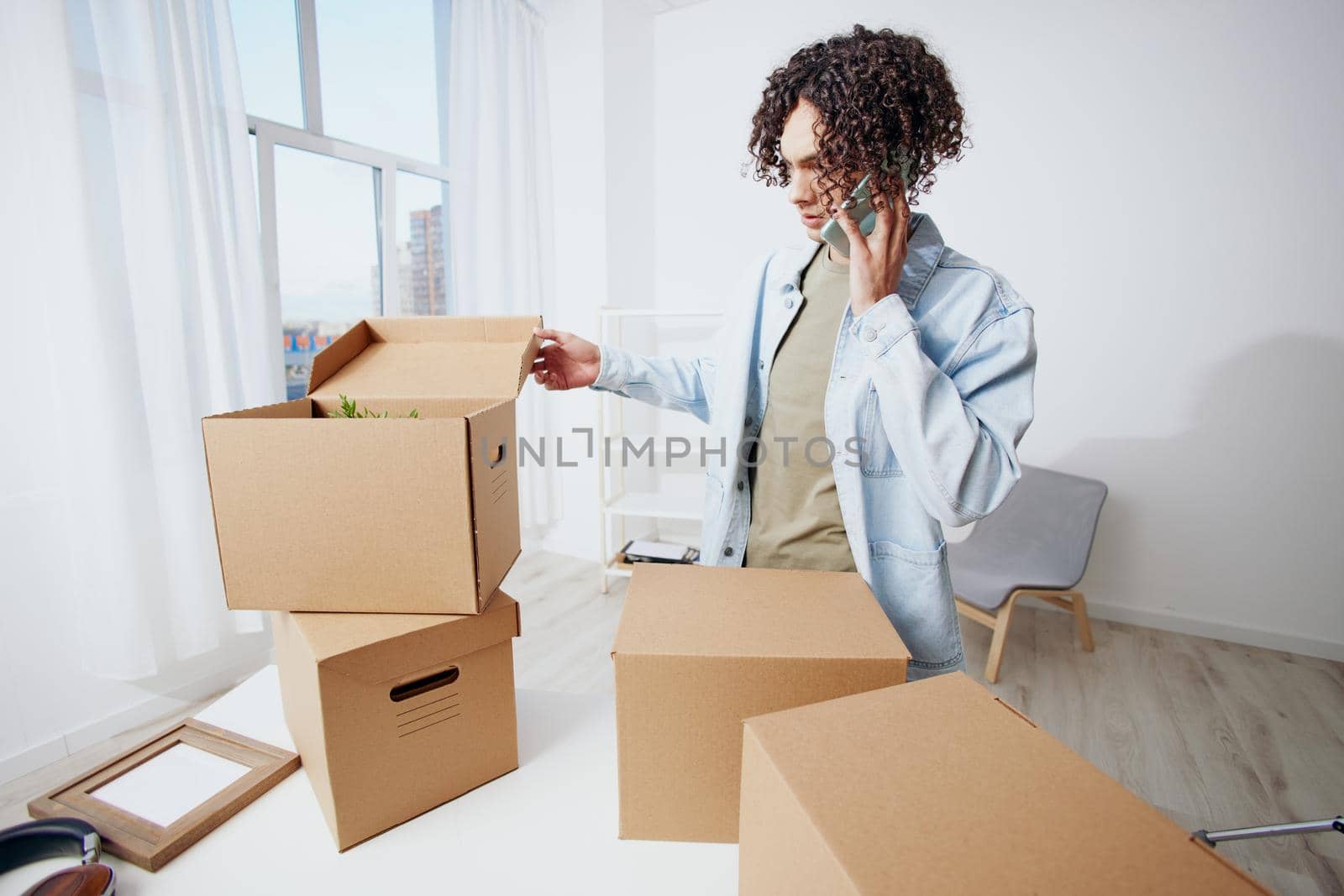 handsome guy cardboard boxes in the room unpacking with phone Lifestyle by SHOTPRIME