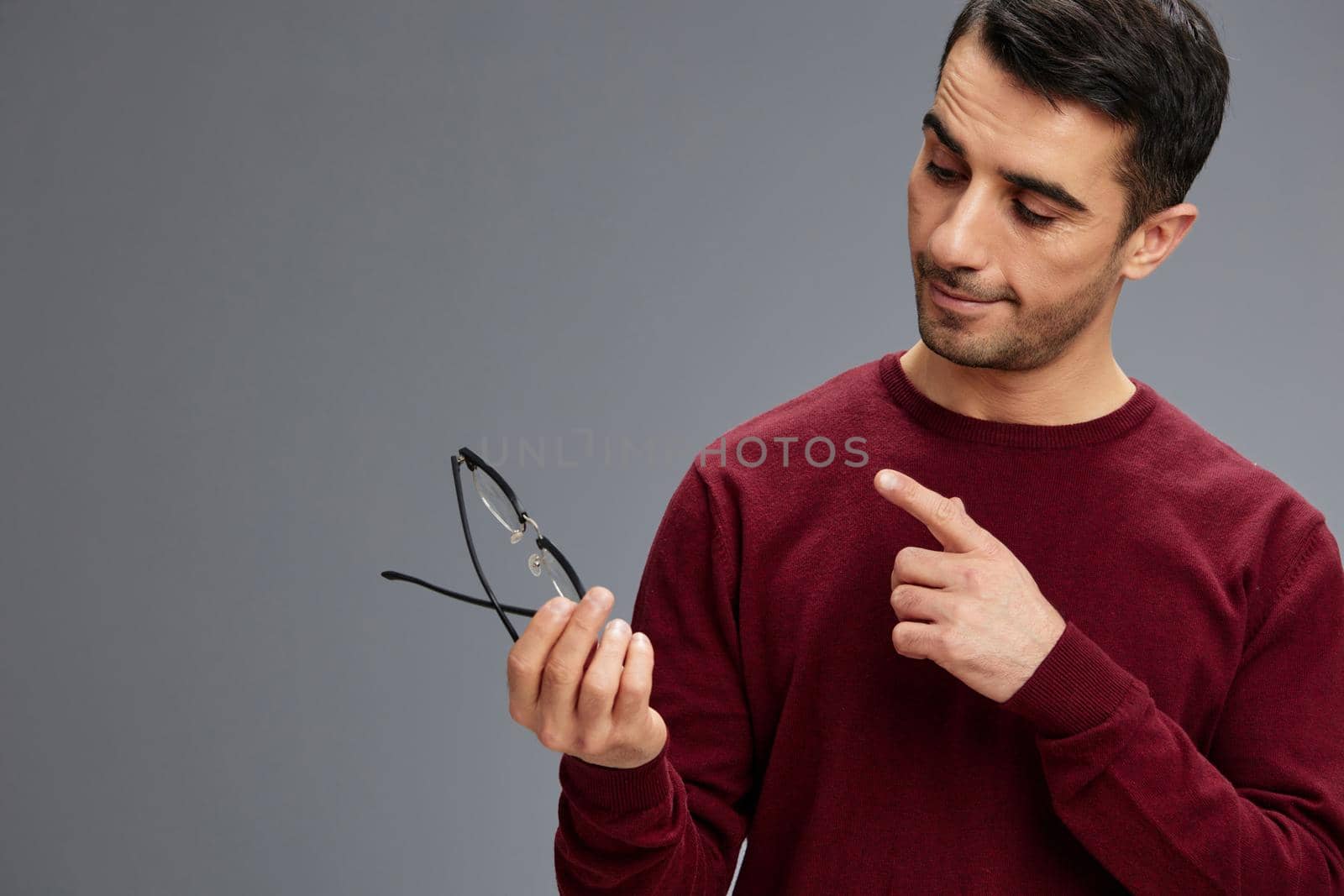 handsome man eyeglasses in hand posing gesture with hands red sweater elegant style. High quality photo