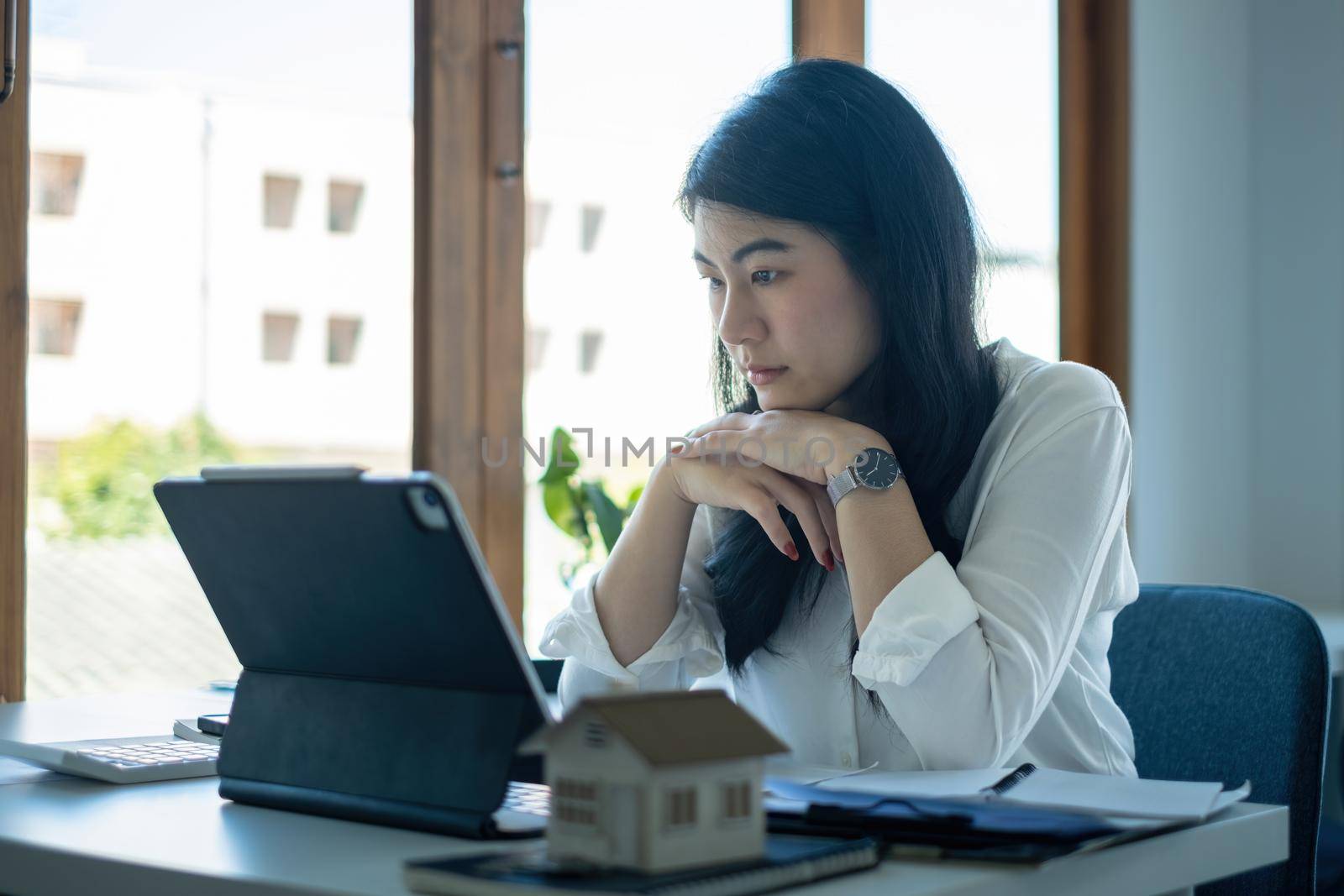 A stressed woman holding and checking house model .Real Estate House Appraisal And Inspection and Insurance concept. by itchaznong