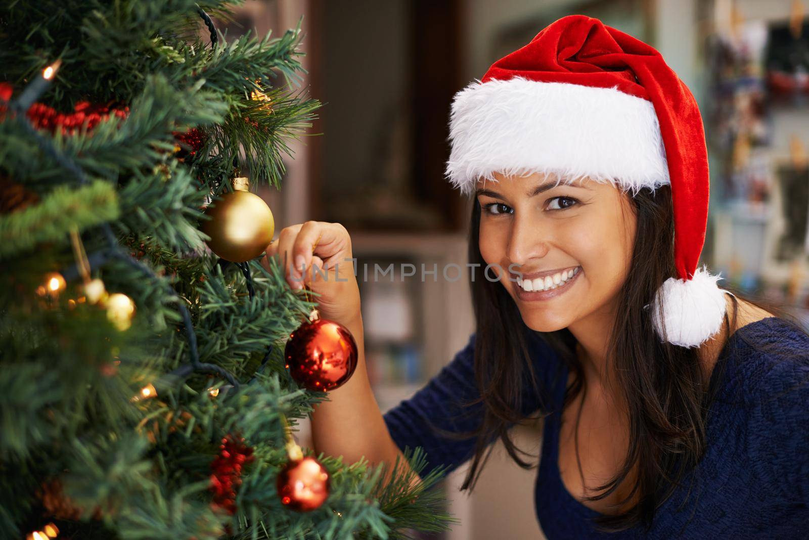 Portrait of a beautiful young woman decorating a Christmas tree.