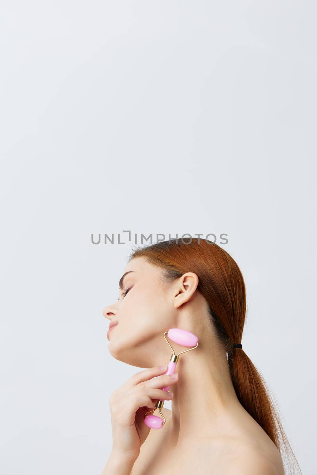 pretty woman pink quartz roller scraper skin care massage bare shoulders isolated background. High quality photo