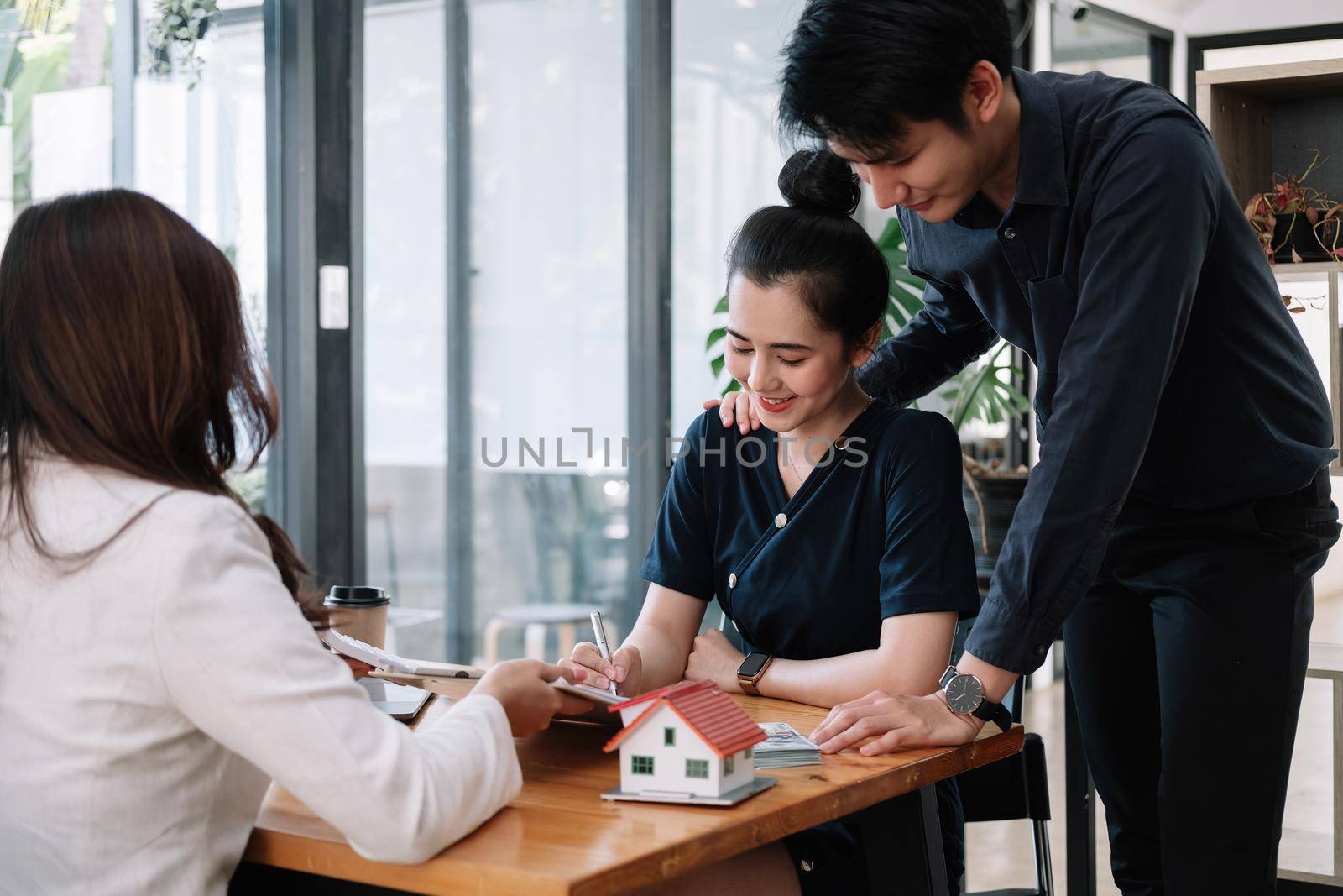 Real estate agent offer hand for customer sign agreement contract signature for buy or sell house. Happy asian couple signing a contract together at office. Real estate agreement concept