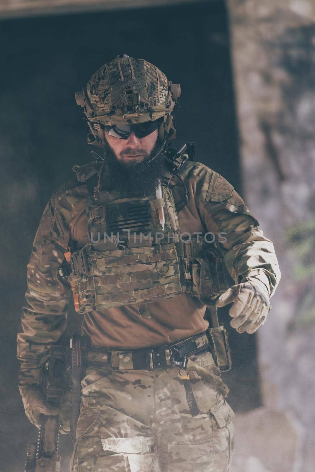 A bearded soldier in a special forces uniform walks through an abandoned building after a successful mission. Selection focus. High-quality photo