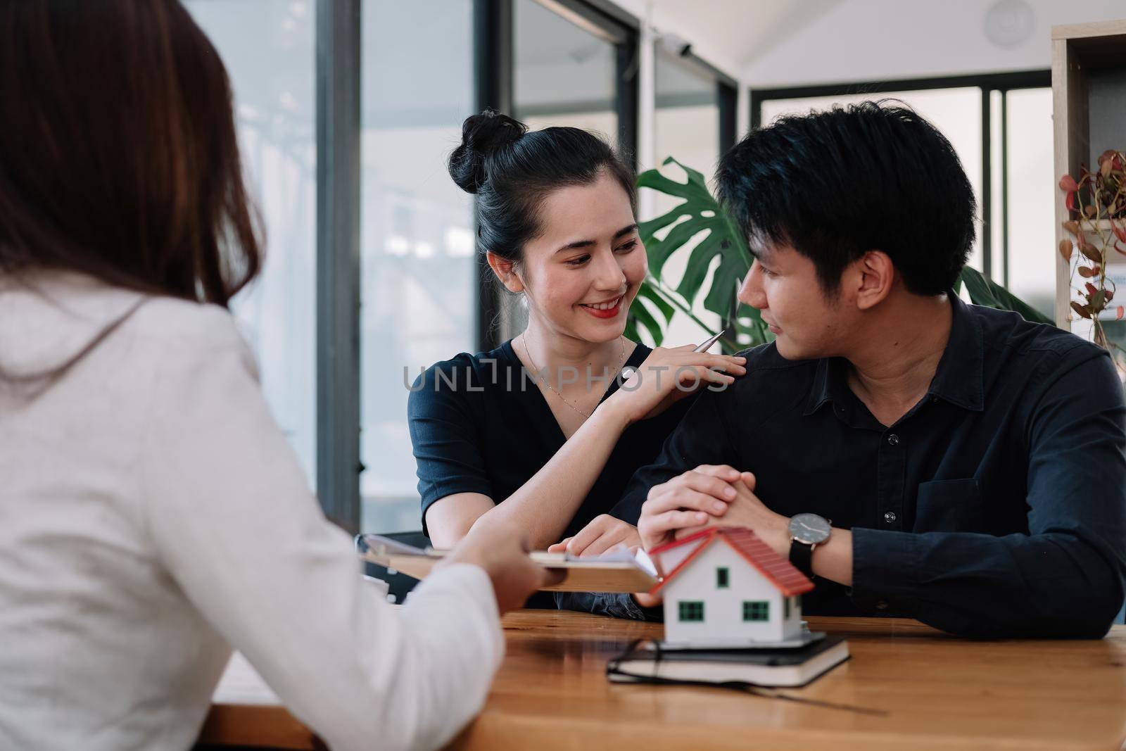Real estate agent offer hand for customer sign agreement contract signature for buy or sell house. Happy asian couple signing a contract together at office. Real estate contact agreement concept.