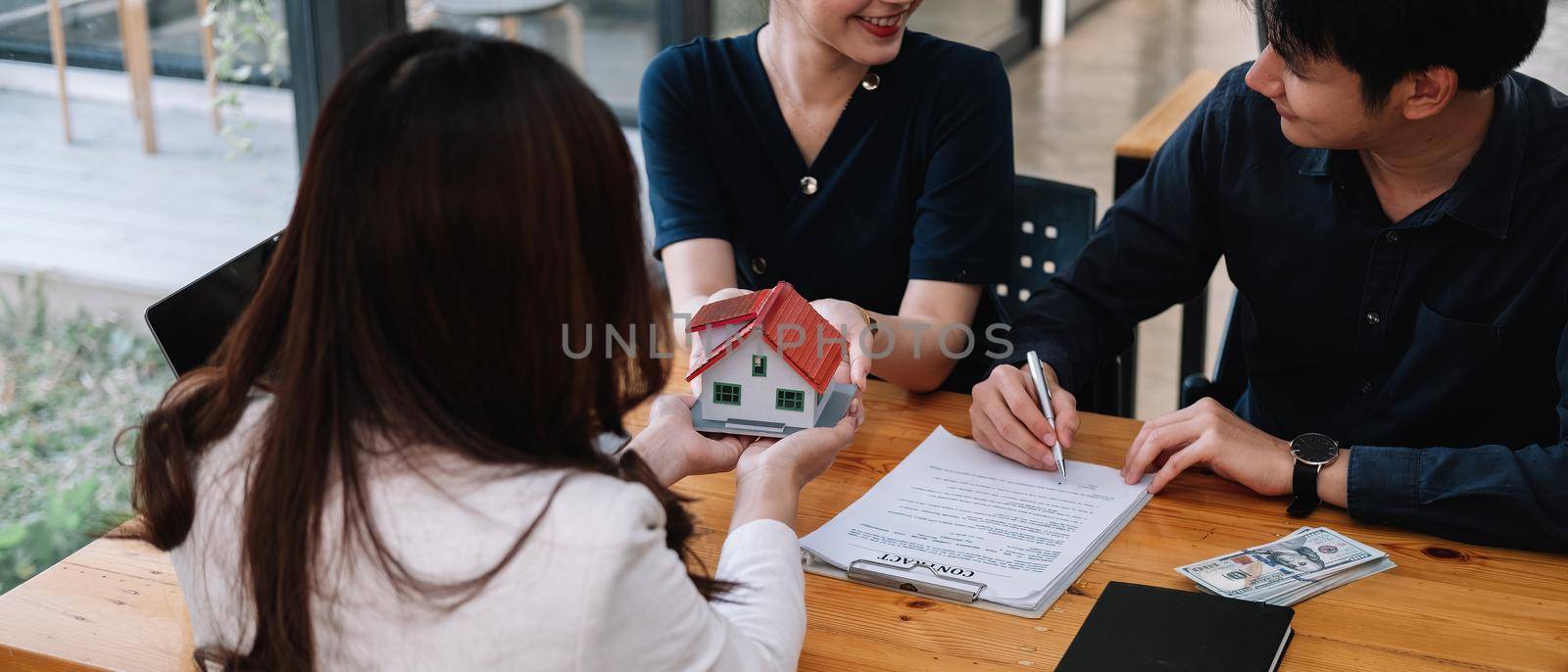 Real estate agent offer hand for customer sign agreement contract signature for buy or sell house. Happy asian couple signing a contract together at office. Real estate contact agreement concept by nateemee