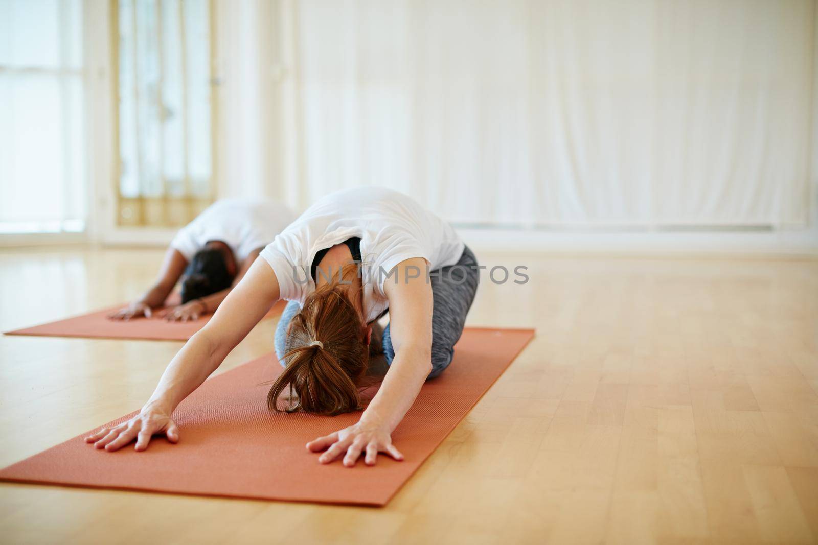 Shot of two women doing yoga together in a studio.