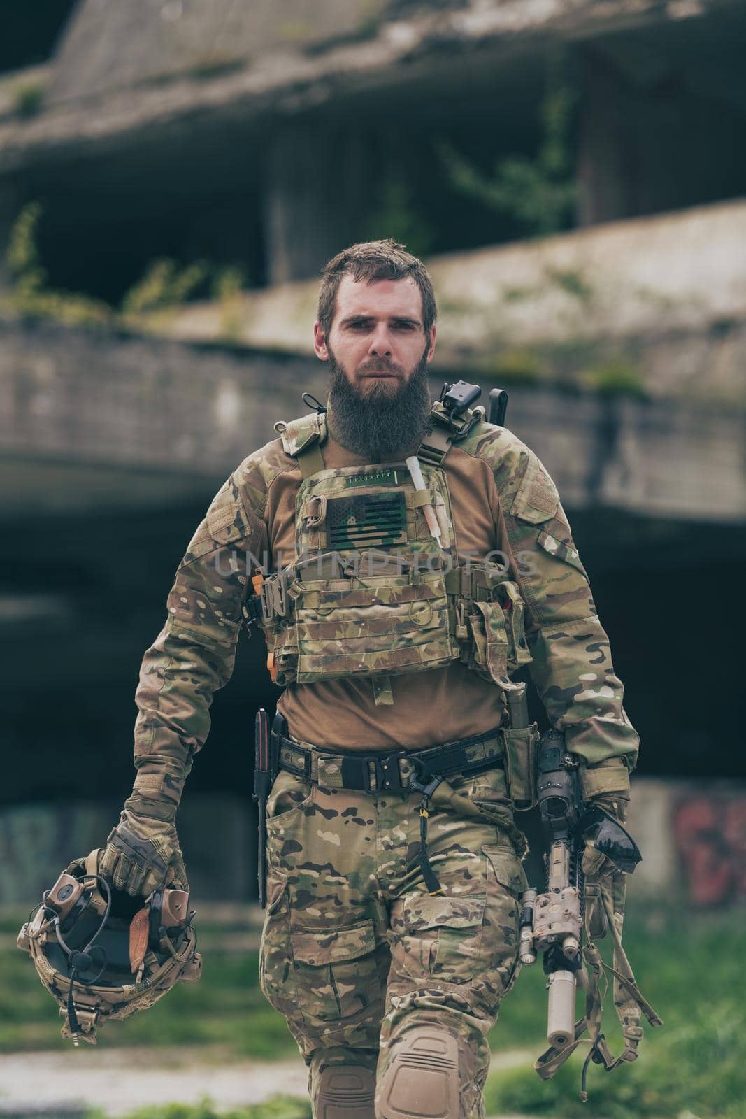 A bearded soldier in a special forces uniform walks through an abandoned building after a successful mission. Selection focus. High-quality photo