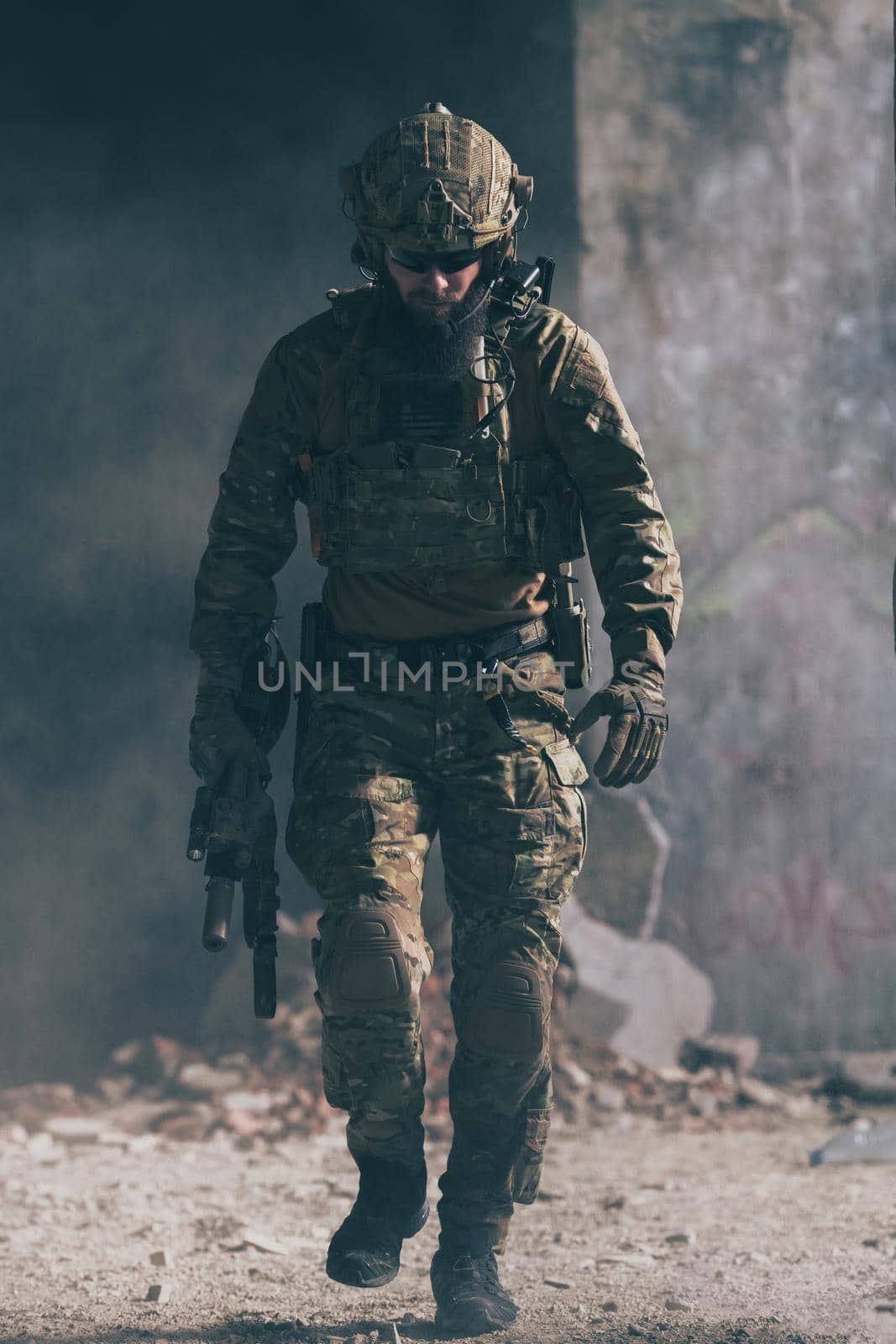 A bearded soldier in a special forces uniform walks through an abandoned building after a successful mission. Selection focus. High-quality photo