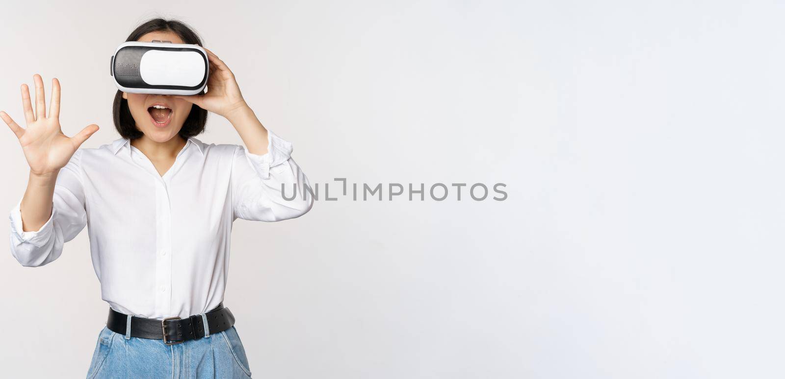 Vr chat. Asian girl saying hello in virtual reality glasses, smiling enthusiastic, concept of communication and future technology, white background by Benzoix