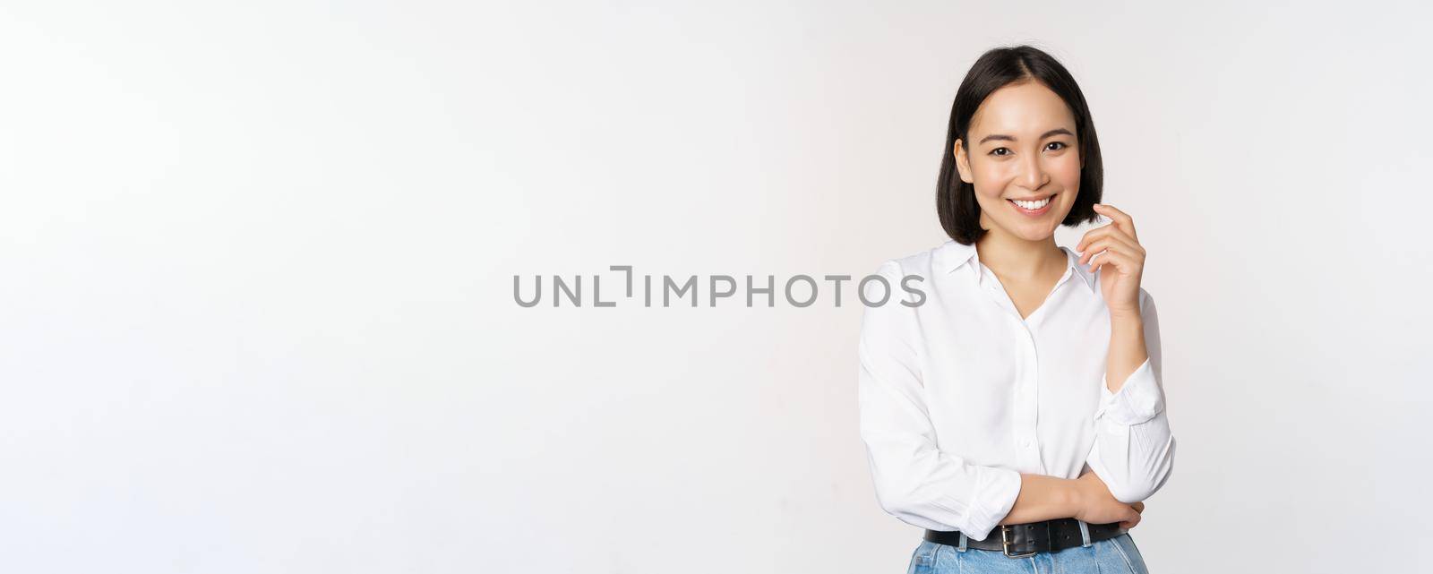 Young asian woman, professional entrepreneur standing in office clothing, smiling and looking confident, white background by Benzoix