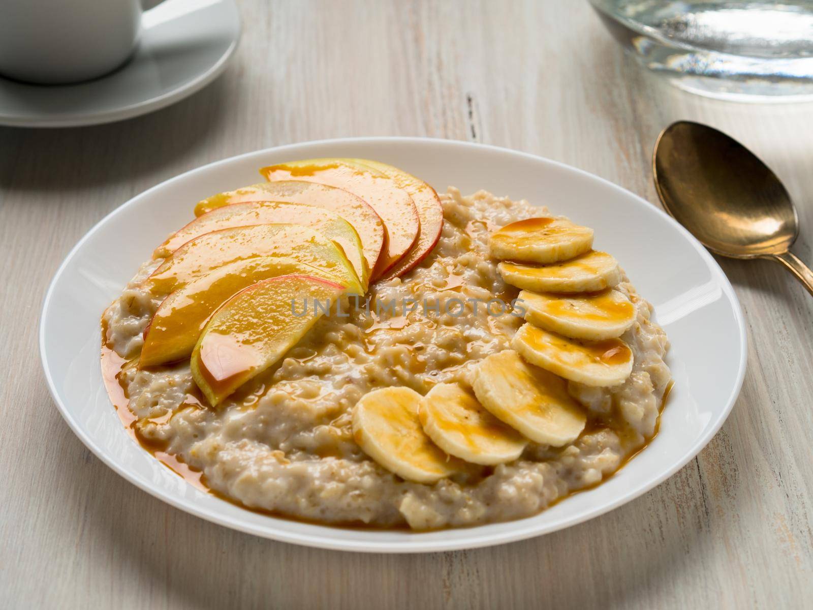 Healthy Breakfast in the morning - oatmeal with fruit and honey, slices of apples and bananas, caramel syrup. Selective focus