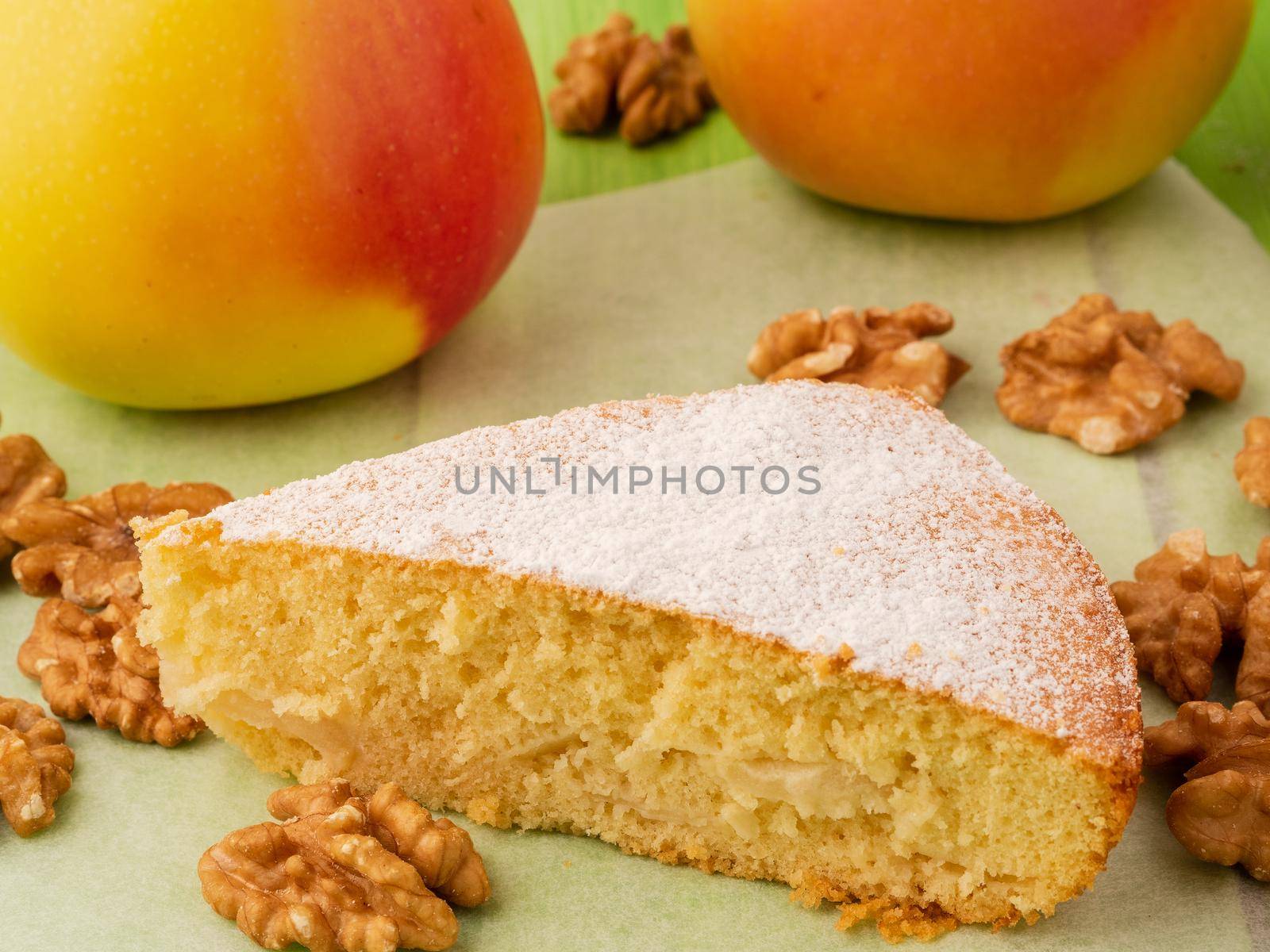 a piece of Charlotte on parchment, nuts and apples. Apple pie biscuit dough decorated with icing sugar by NataBene