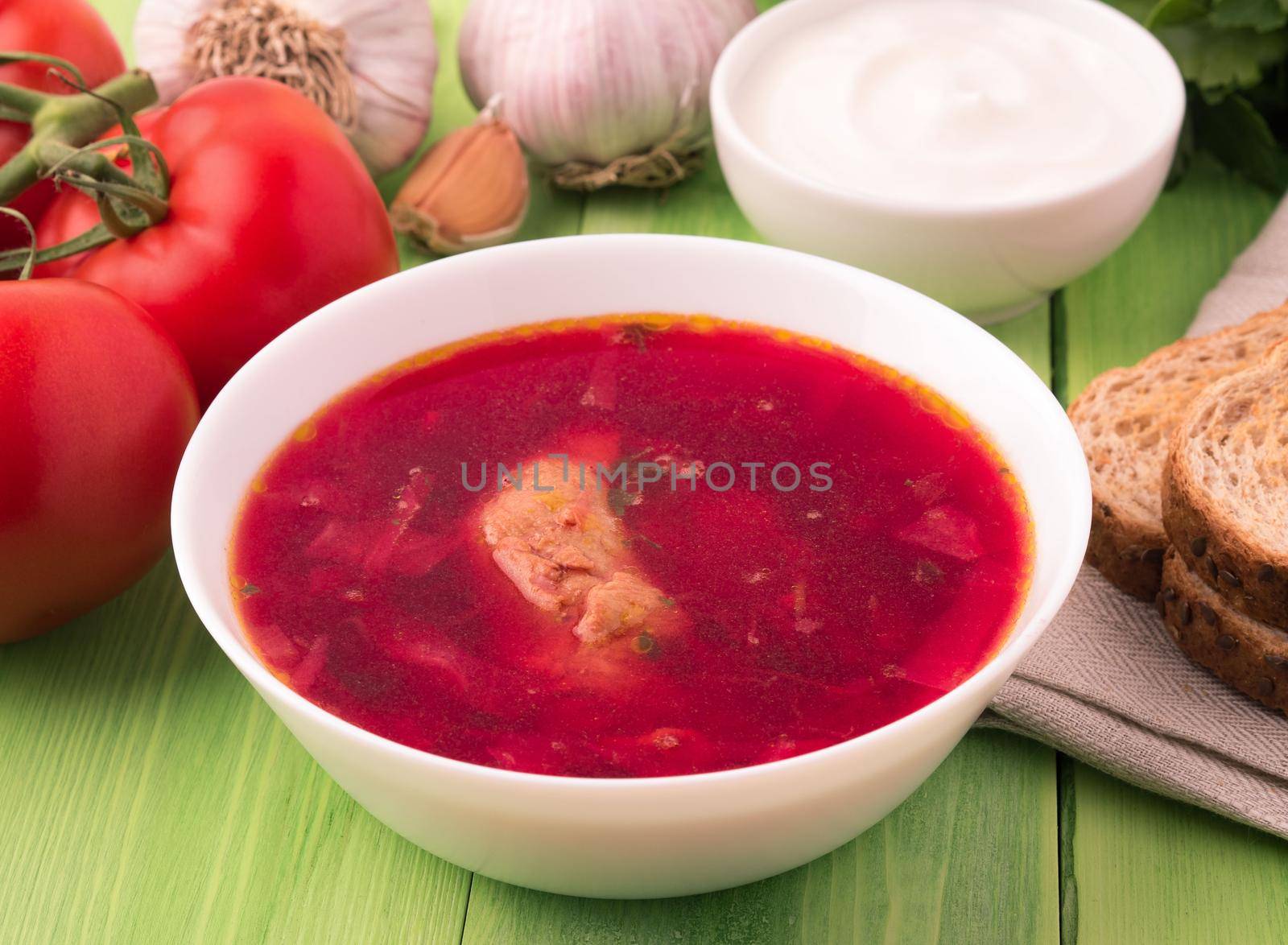borscht - a soup based on beet, it has a characteristic red color. A traditional dish of the Eastern Slavs, the first main meal of the South Russian and Ukrainian cuisine. Dish, garlic, greens, bread, tomatoes and sour cream