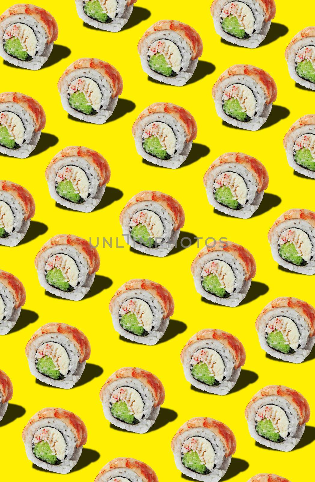 Rolls with soft cheese, crab meat and cucumber slices topped with shrimp fillet on yellow background. Concept of Japanese cuisine traditions. Food pattern