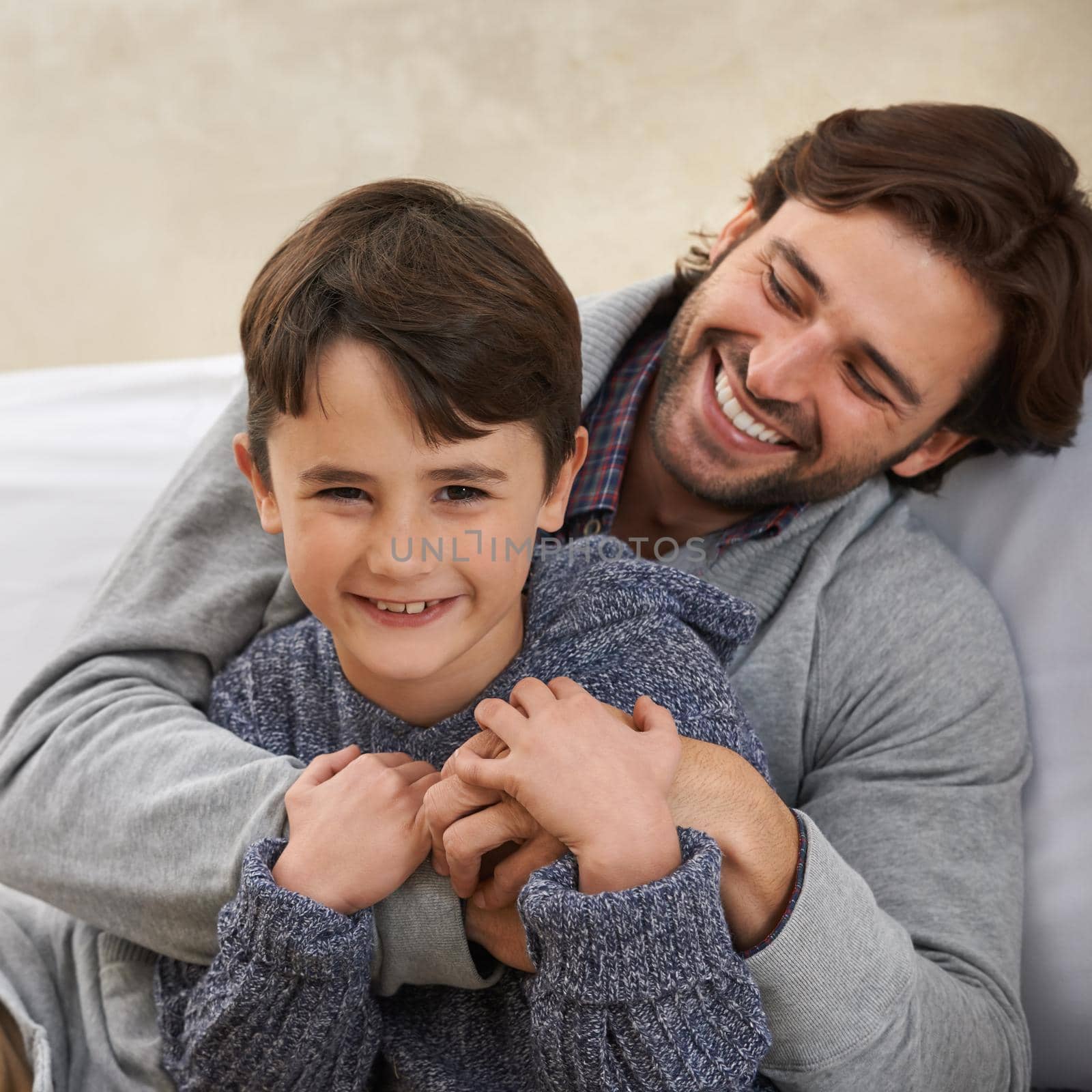 Portrait of a young father and son sitting on the sofa.