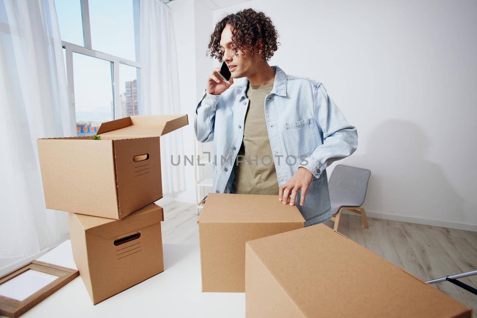 A young man unpacking things from boxes in the room sorting things out. High quality photo