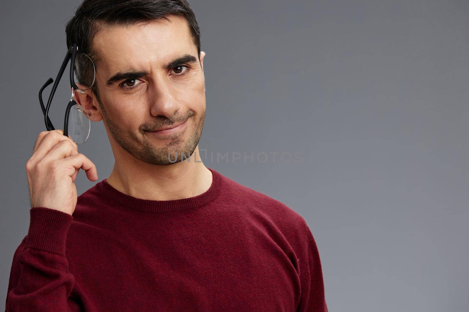 manager holding glasses near face in a red sweater posing self confidence isolated background. High quality photo