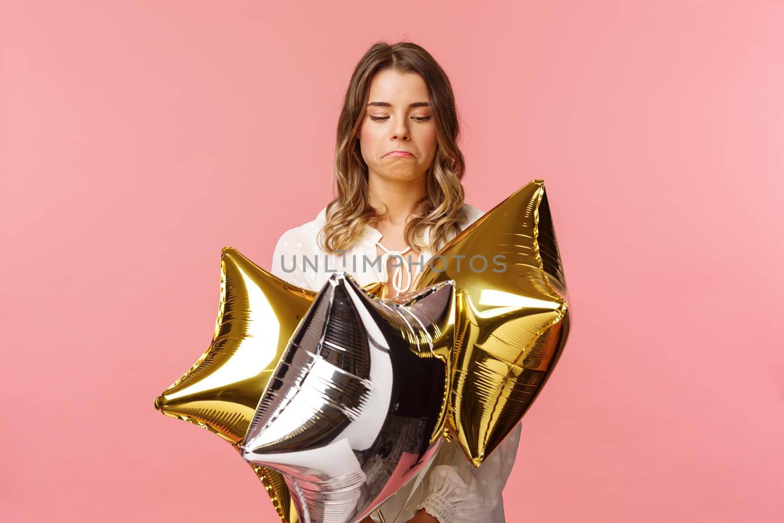 Holidays, celebration and women concept. Portrait of satisfied good-looking blond girl make not bad face, pulling lips down and nod in approval, looking at cool star-shaped balloons.