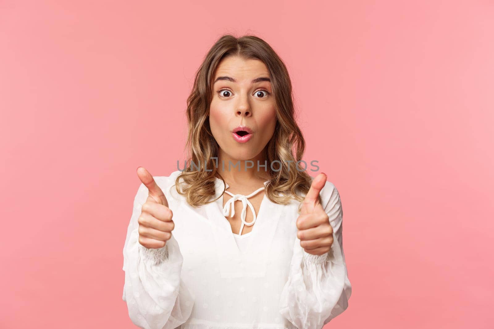 Close-up portrait of impressed blond girl showing thumbs-up look astonished and disbelief as processing fascinating performance she saw, leave positive review, standing pink background by Benzoix