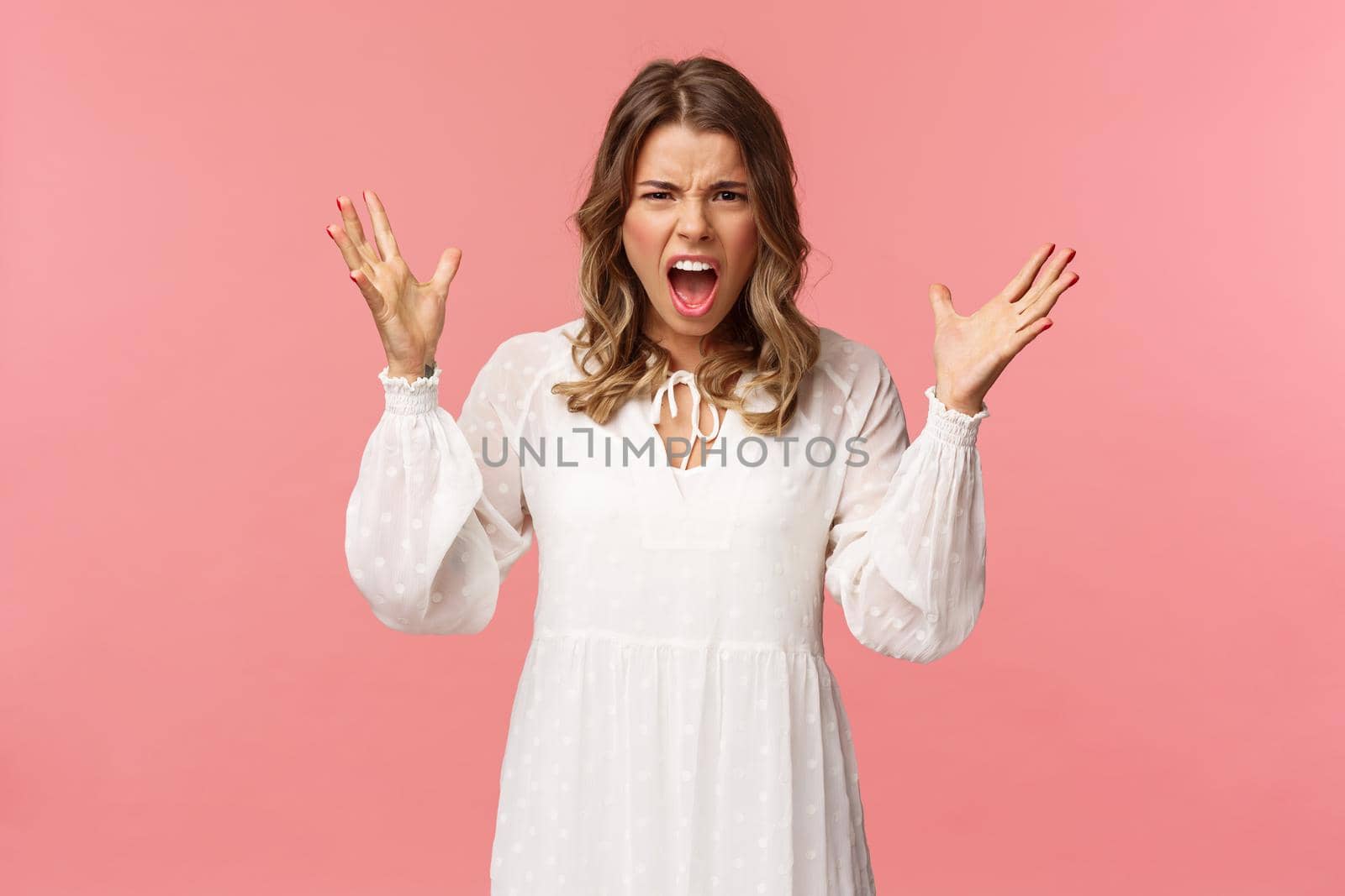 Portrait of tensed young angry blond girlfriend yelling, shouting and freaking-out over huge mess, raise hands up dismay grimacing aggressive, frowning and shouting during argument by Benzoix