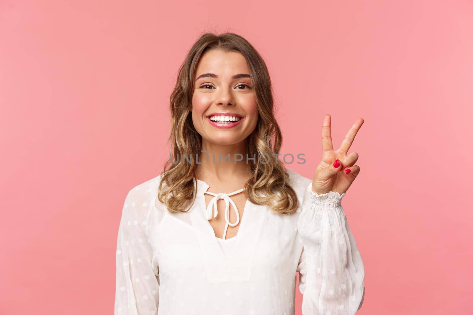 Close-up portrait of romantic lovely smiling girl with blond short hair, wearing white dress, show peace sign enjoying spring, grinning and look camera over pink background by Benzoix