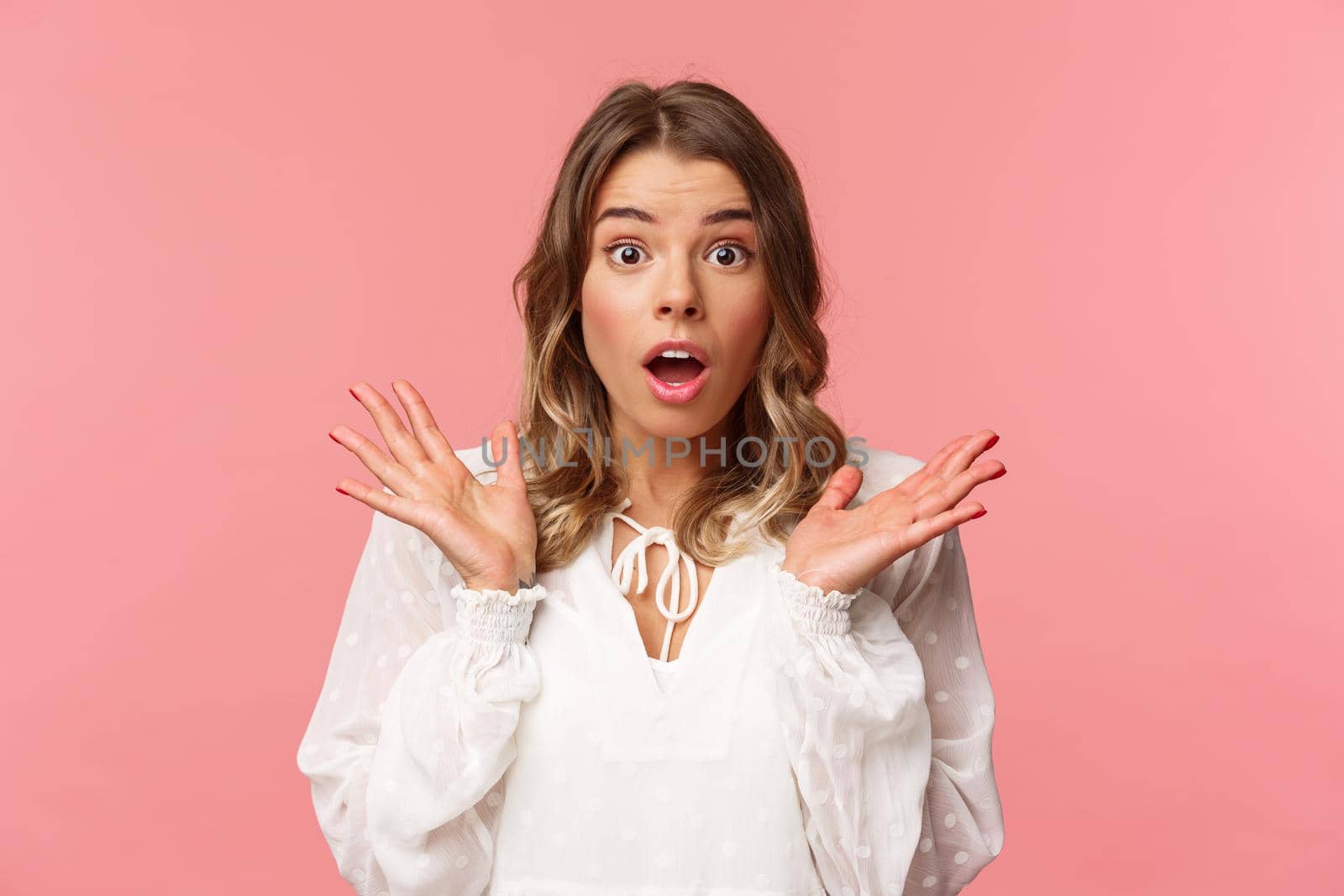 Close-up portrait of impressed and surprised blond girl hear something stunning and impressive happened, drop jaw spread hands sideways, look astonished with news, pink background by Benzoix