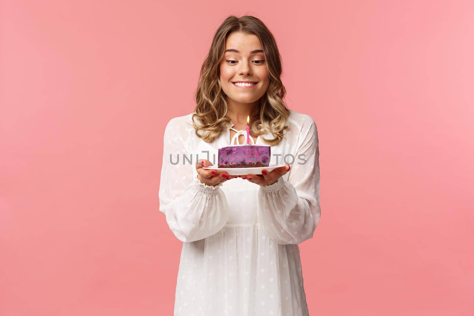 Holidays, spring and party concept. Portrait of dreamy, happy birthday girl feeling excitement and joy celebrating b-day, biting lip and smiling as making wish blowing candle on cake by Benzoix
