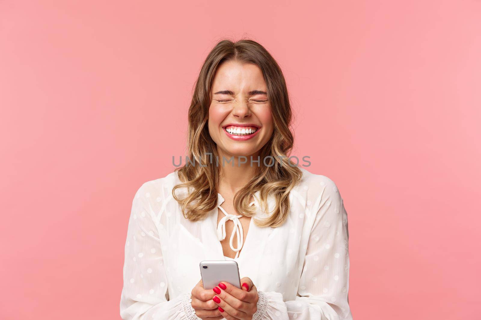 Close-up portrait of carefree tender, lovely blond girl in white dress, laughing over funny joke or message, holding mobile phone, close eyes and giggle at something hilarious, pink background by Benzoix