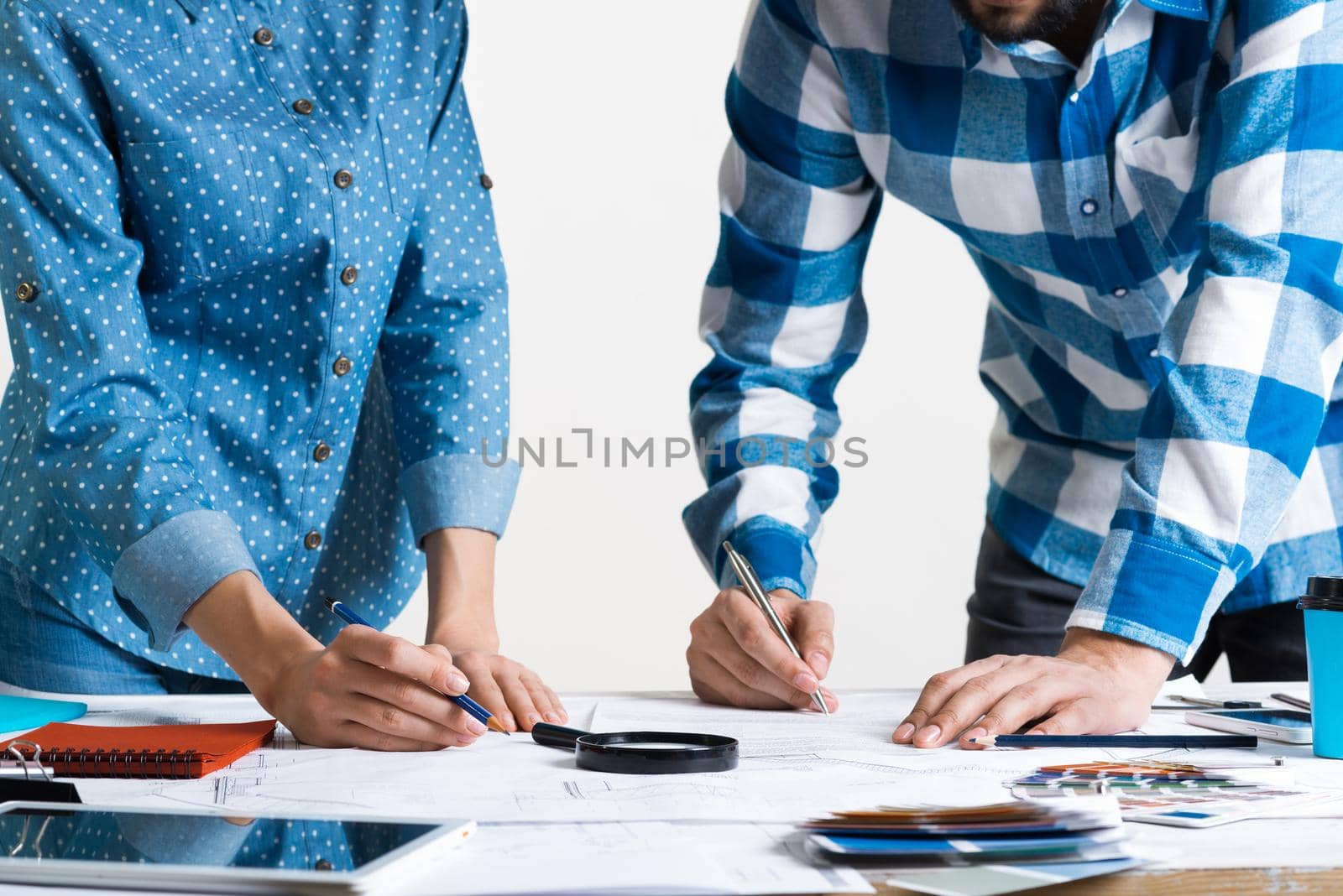 Man writing with pen on technical drawing. Creative team of designers together working with construction blueprint. Thorough study and approval of design project. Architecture studio concept.