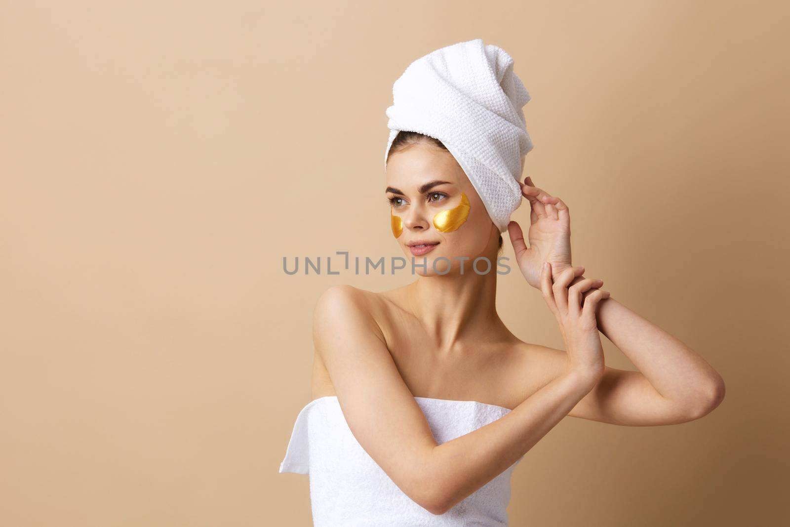 portrait woman with a towel on his head gesturing with his hands skin care beige background. High quality photo