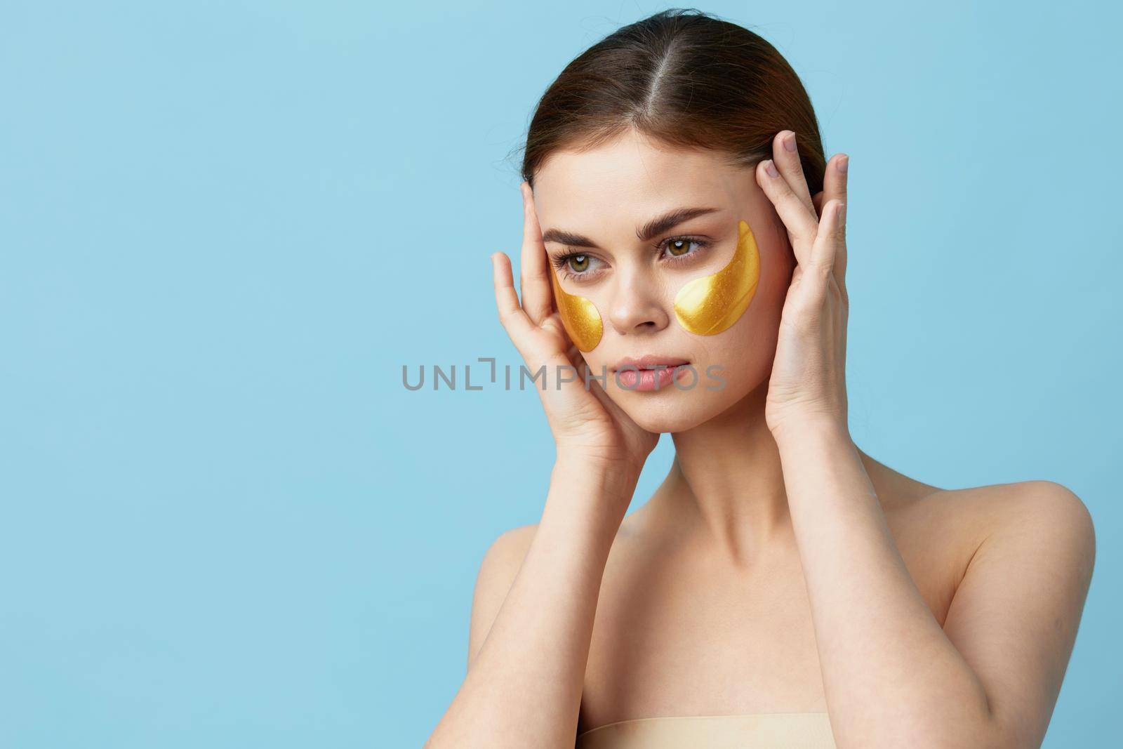 pretty woman skin care face patches bare shoulders hygiene blue background. High quality photo