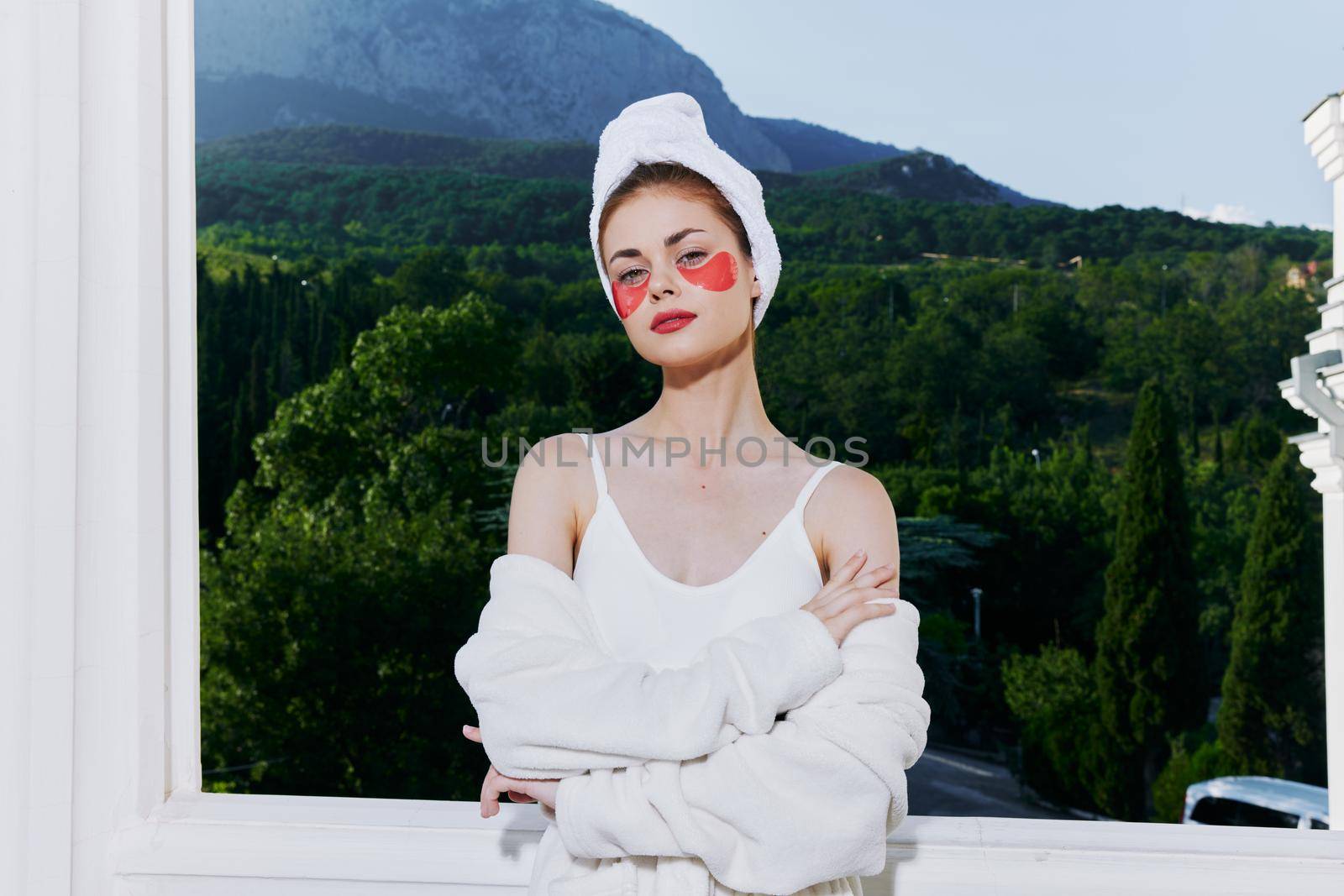 Woman in a bathrobe stands in a robe against the backdrop of mountains with patches on his face close-up. High quality photo