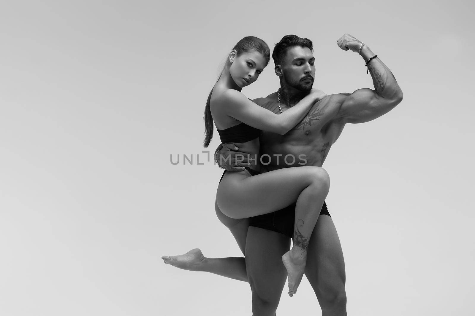 Black and white tattooed shirtless man and seductive topless woman looking away