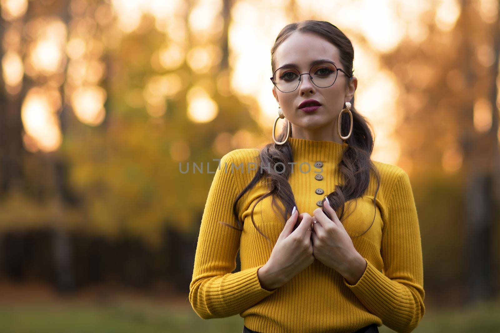 Charming young woman standing in autumnal park by 3KStudio