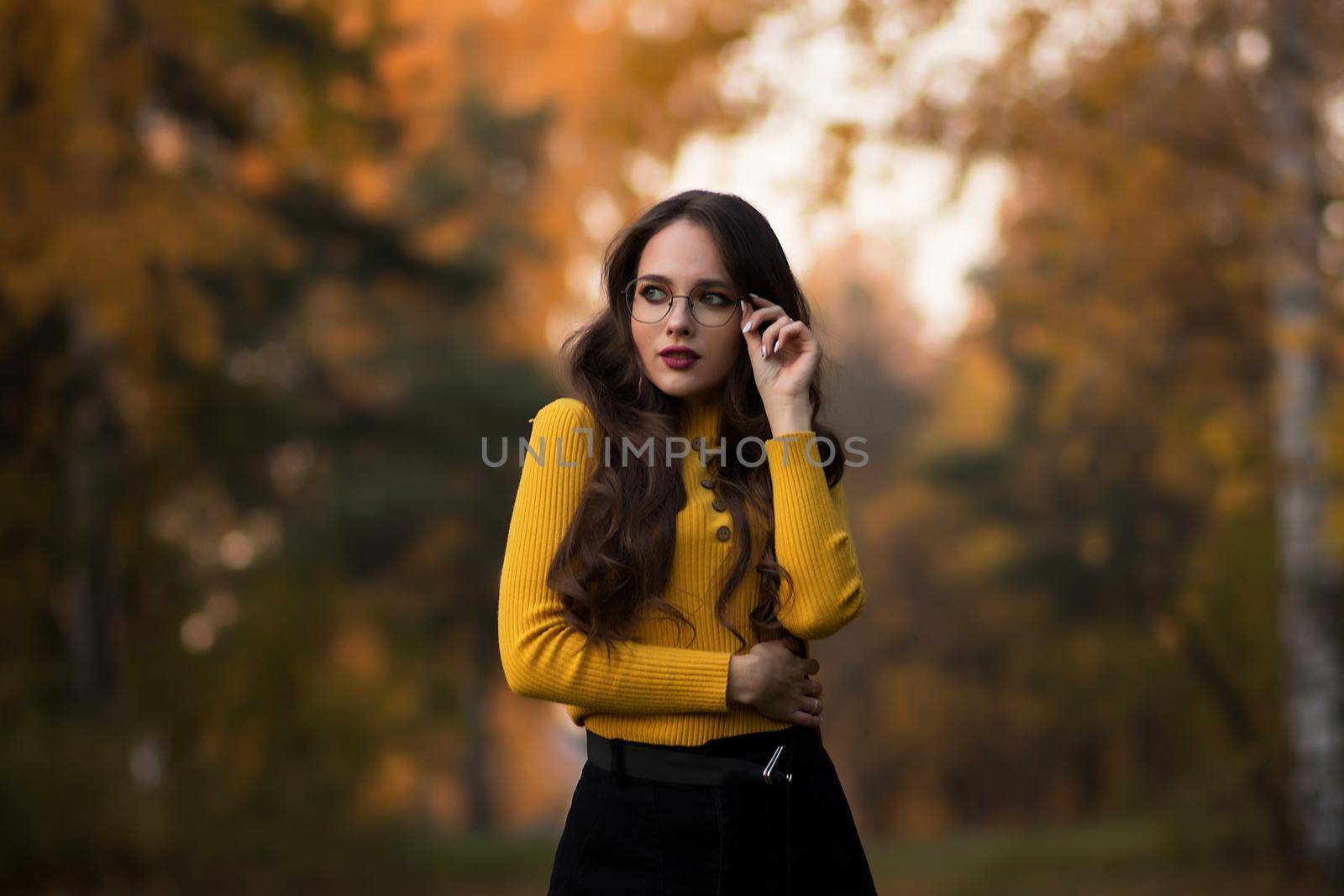 Charming young woman standing in autumnal park by 3KStudio