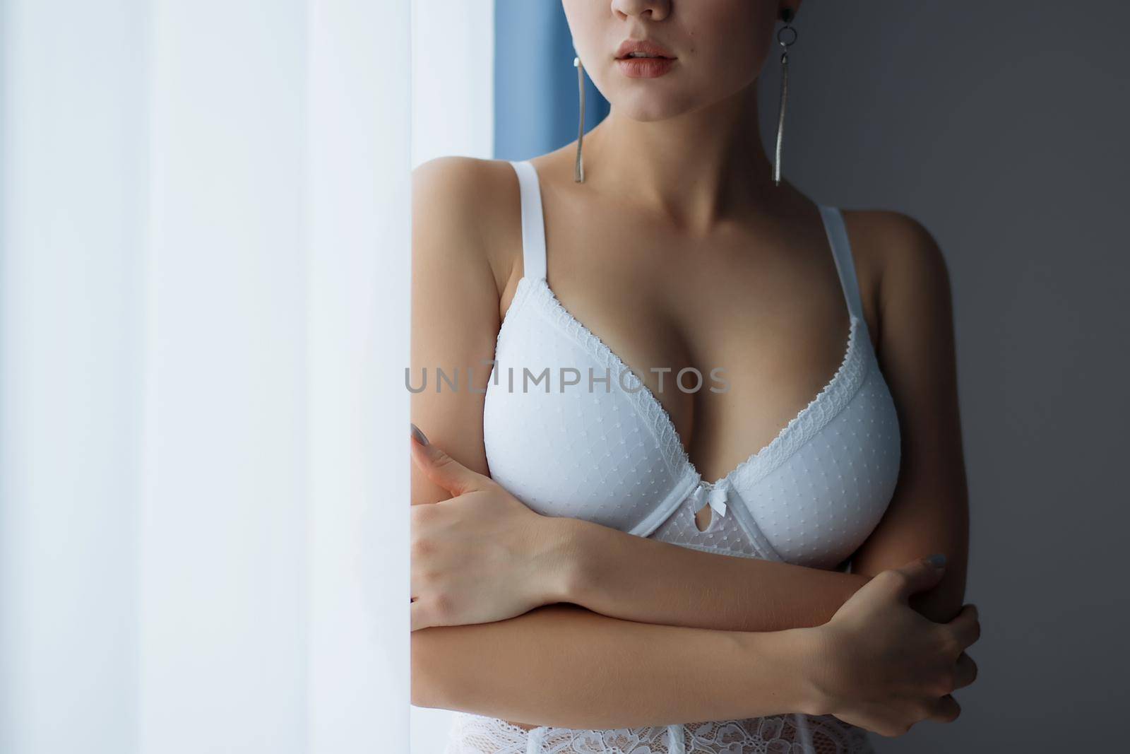 Alluring woman in whiteunderwear standing near window by 3KStudio