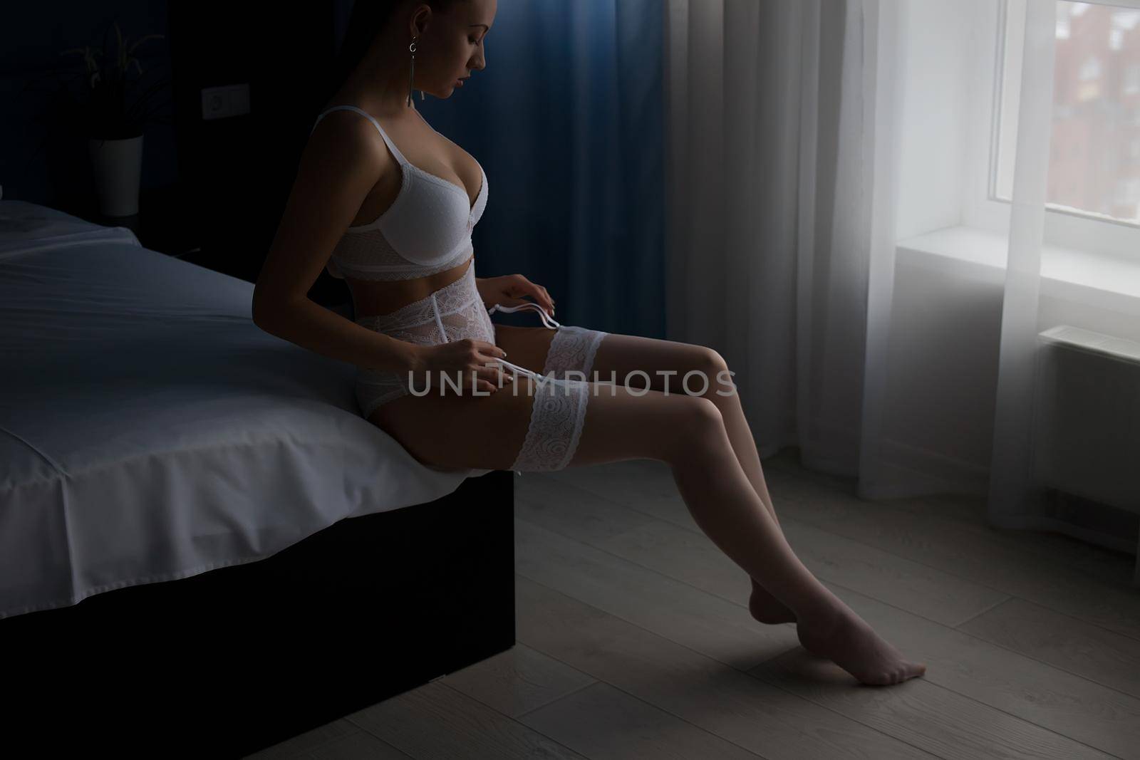 Seductive woman in lingerie sitting on bed by 3KStudio