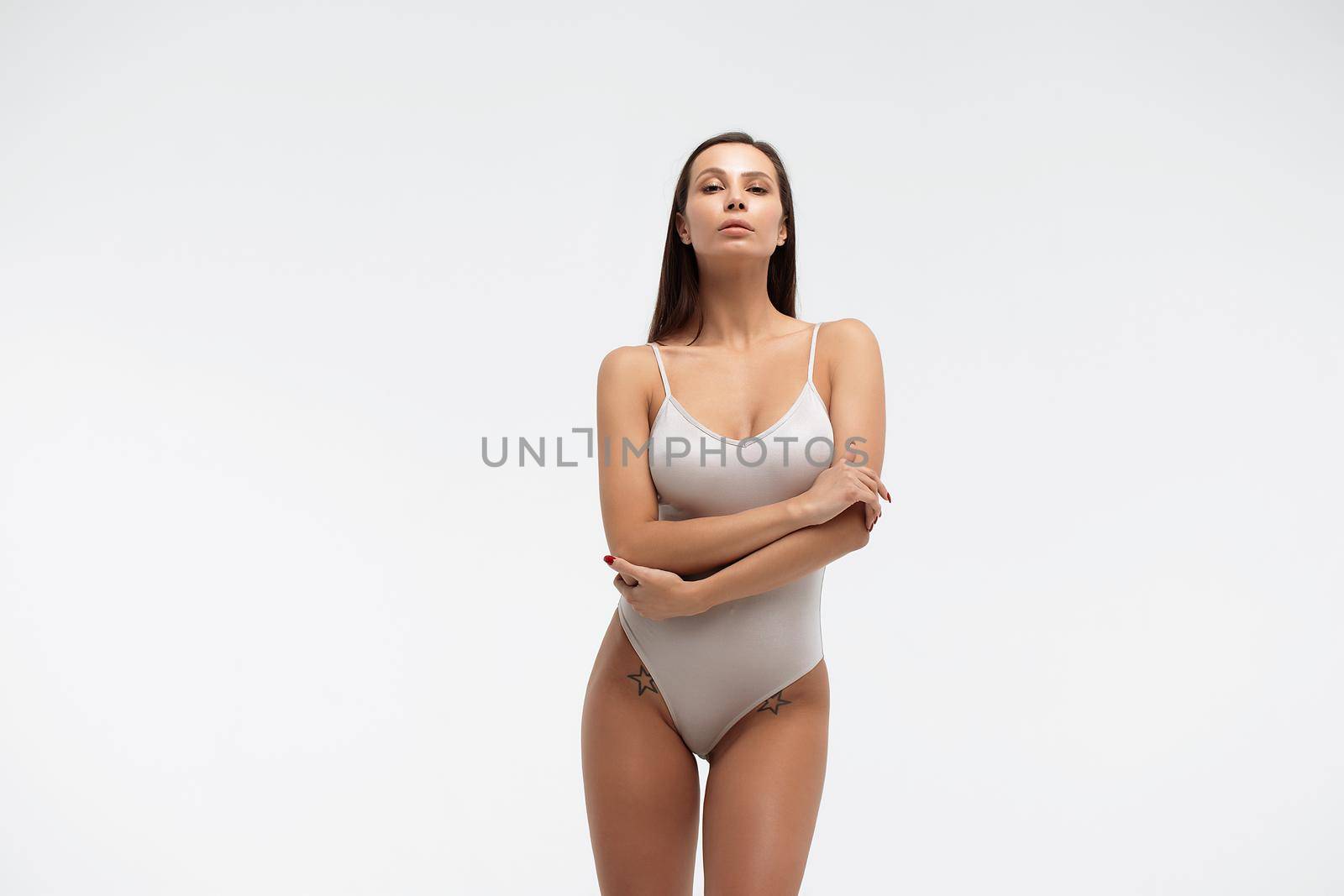 Slim woman in white bodysuit in studio by 3KStudio