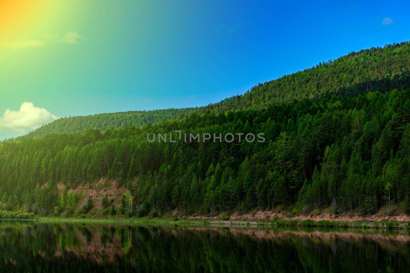 Landscape of the river bank in Siberia. bright juicy colors hilly riverbank and blue clouds.