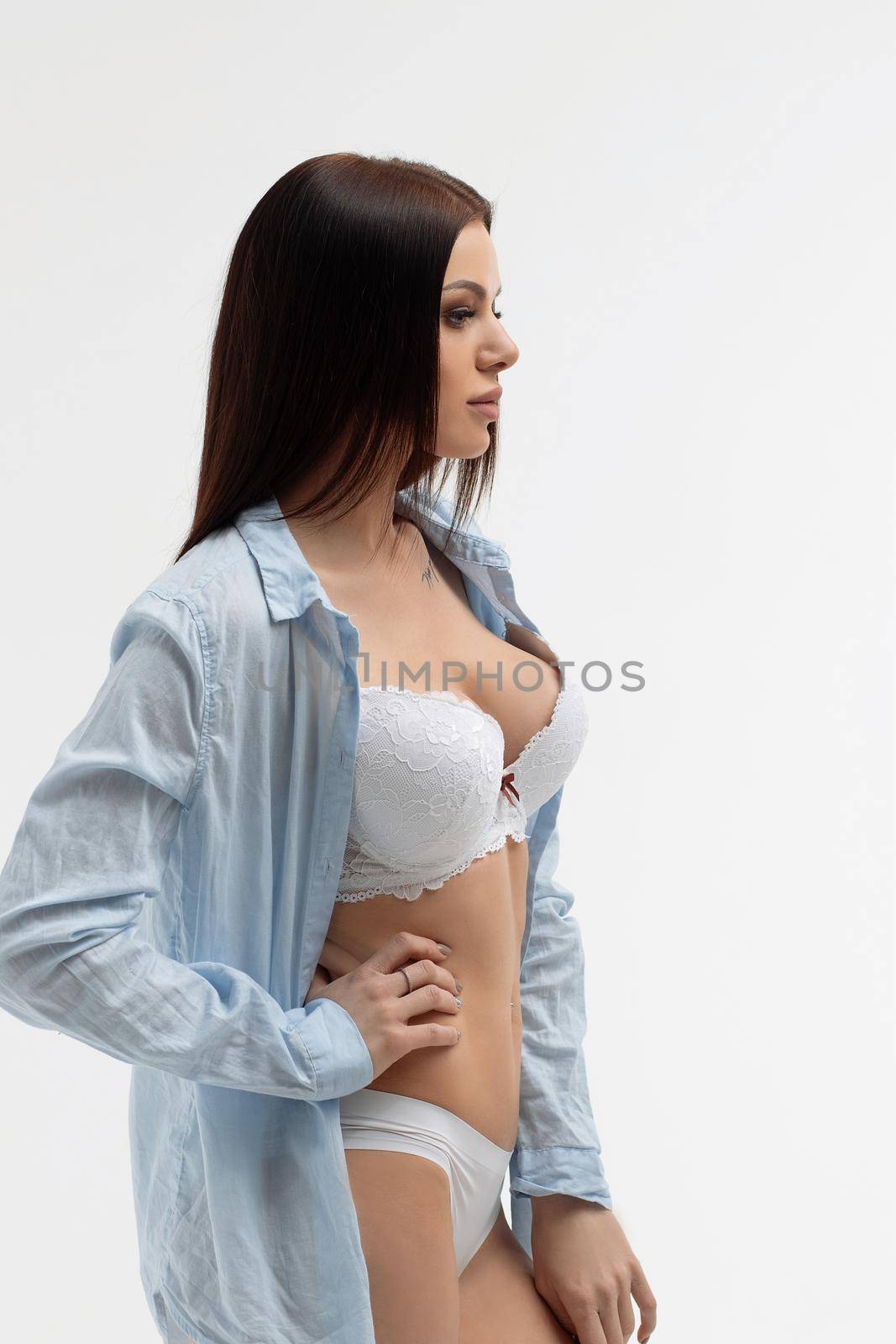 Young sensual woman with straight hair in white underwear and blue shirt looking at camera