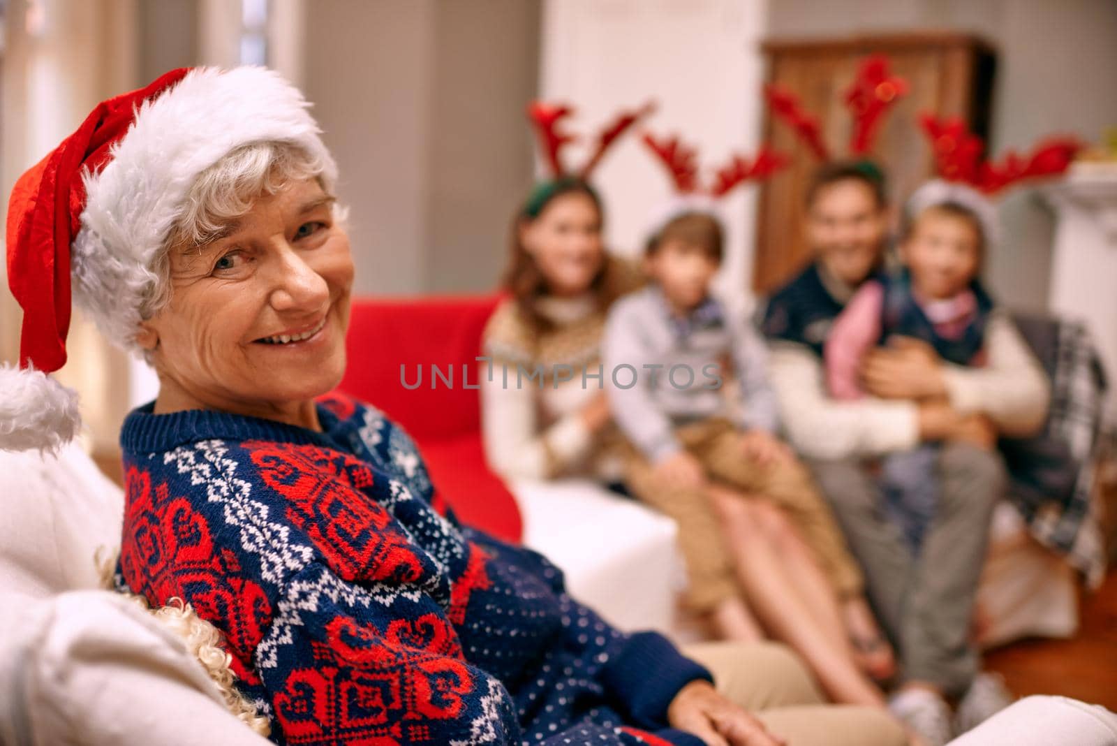 Theres no way Im wearing those antlers. A happy grandmother with her family on Christmas Eve. by YuriArcurs