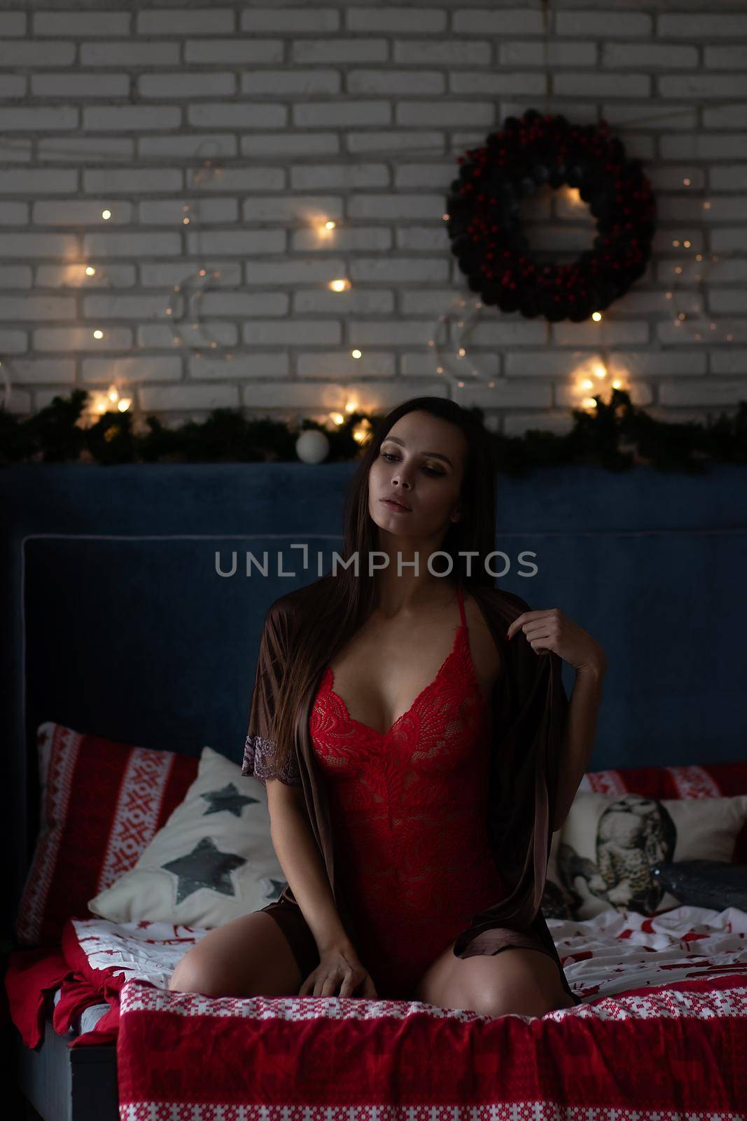 Sensual young woman in elegant lingerie resting on bed during Christmas holidays by 3KStudio