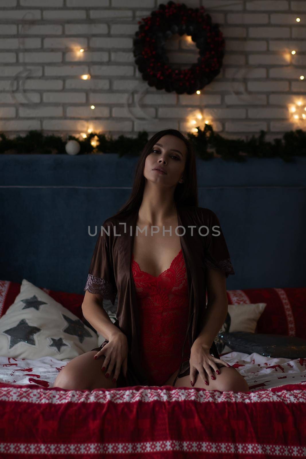 Sensual young woman in elegant lingerie resting on bed during Christmas holidays by 3KStudio