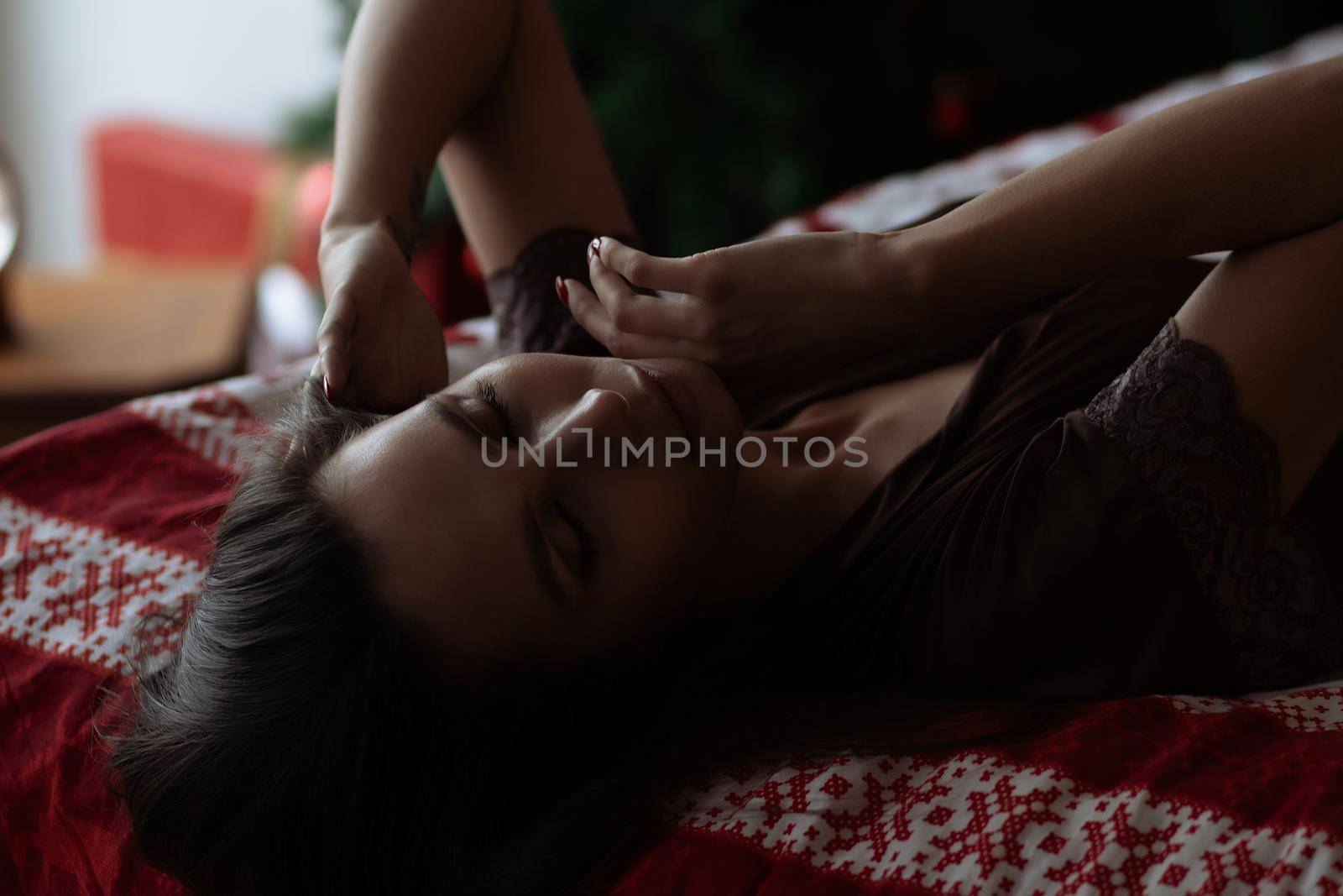 Alluring young lady relaxing on bed with closed eyes during Christmas holidays by 3KStudio