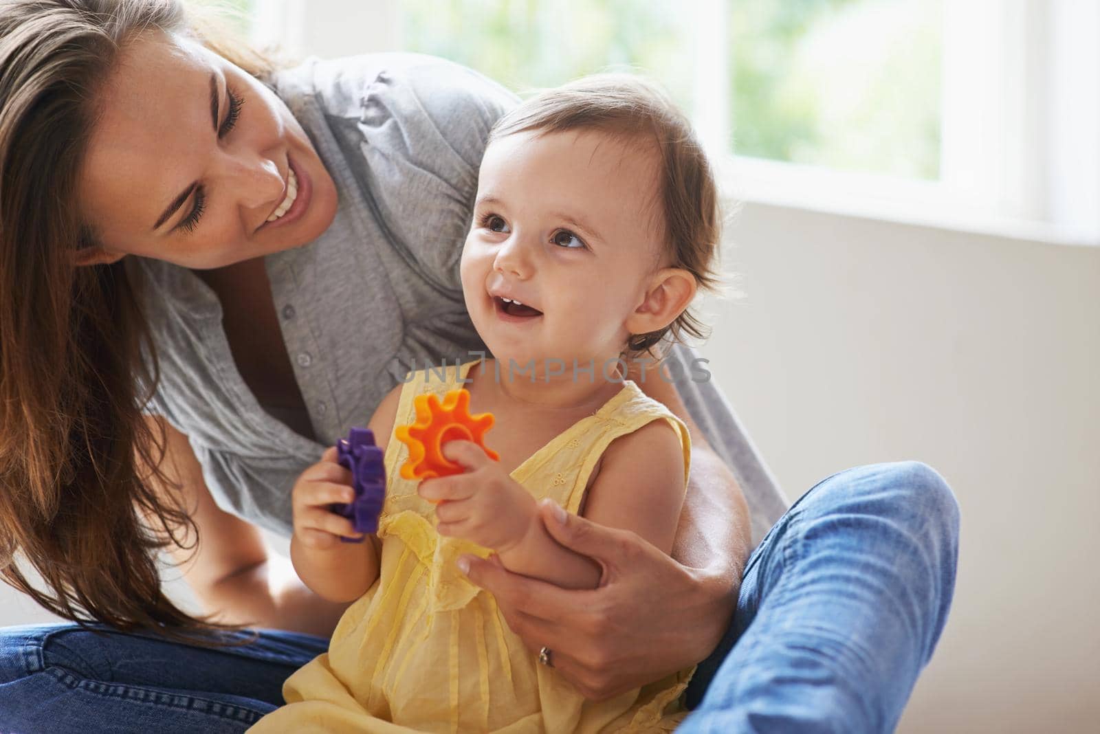 Shot of a cute baby girl sitting on the floor with her mom and playing with toys.