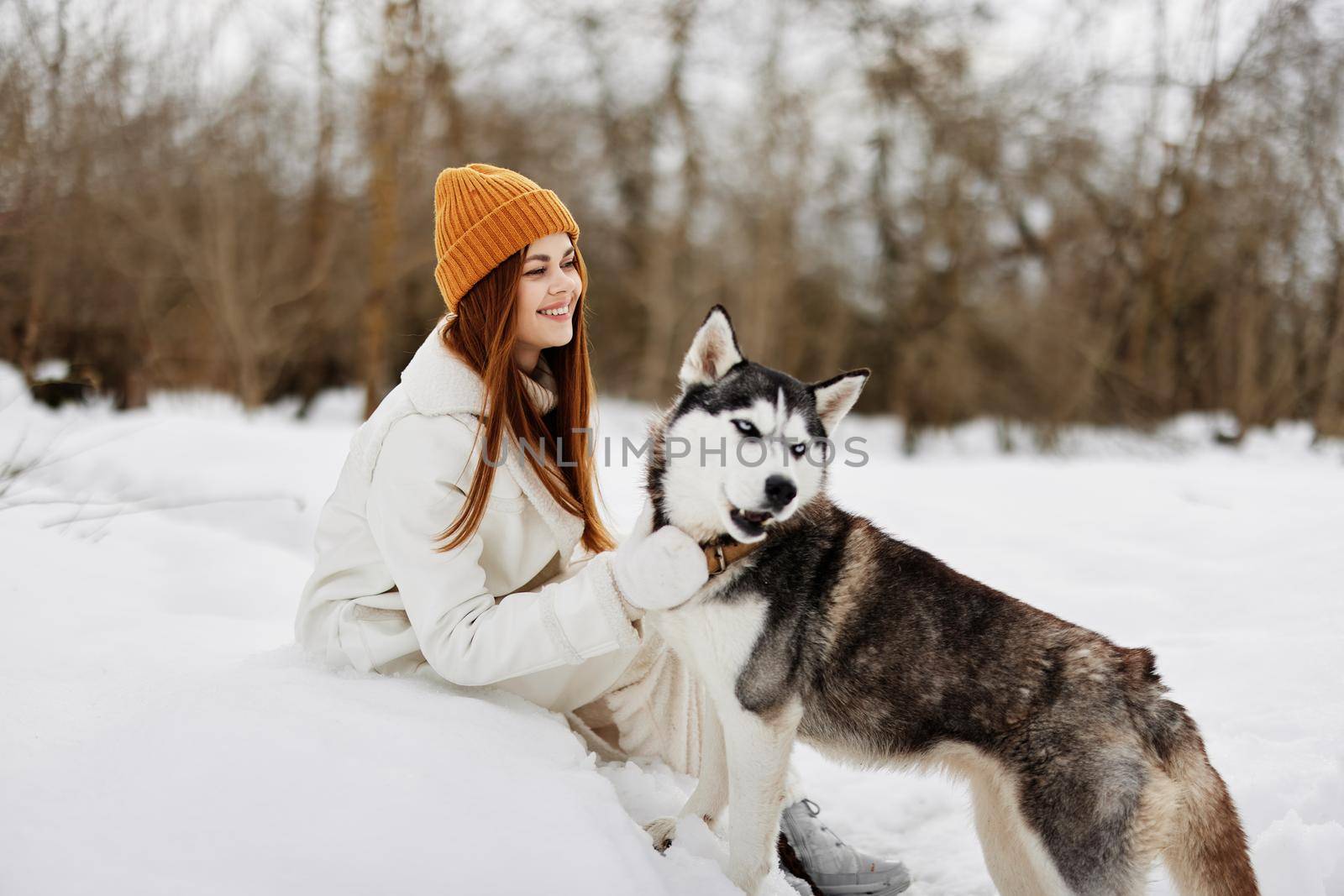 portrait of a woman in the snow playing with a dog fun friendship fresh air. High quality photo