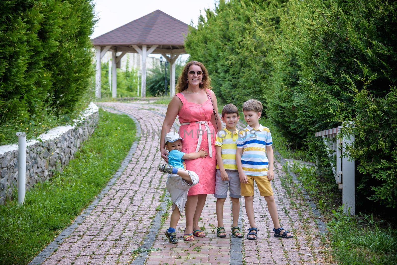 Young woman having fun playing in the park with their children. Boys of primary school age. The family is surrounded by picturesque plants. Games outdoor useful to all.