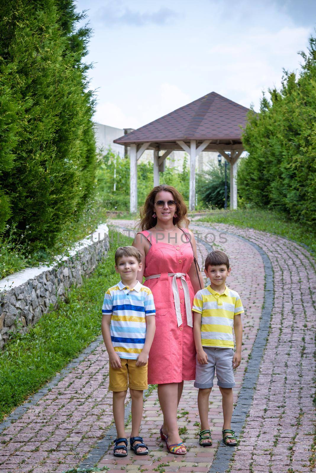 Young woman having fun playing in the park with their children. Boys of primary school age. The family is surrounded by picturesque plants. Games outdoor useful to all by Kobysh