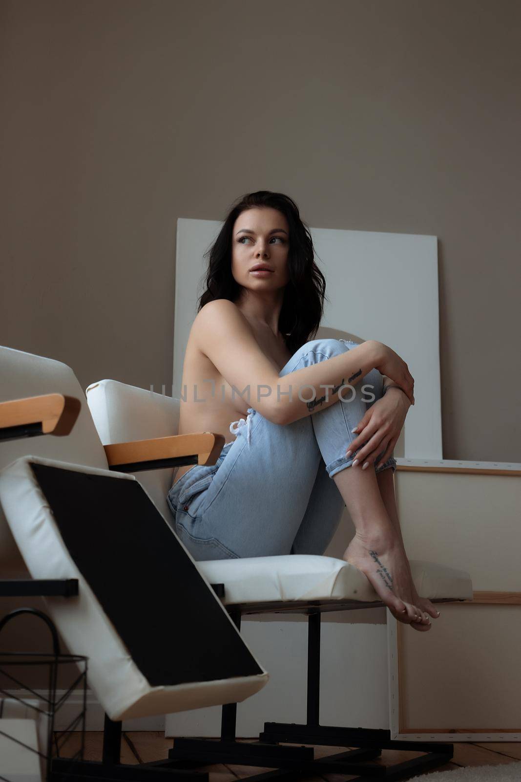 Relaxed topless woman sitting on chair at home by 3KStudio